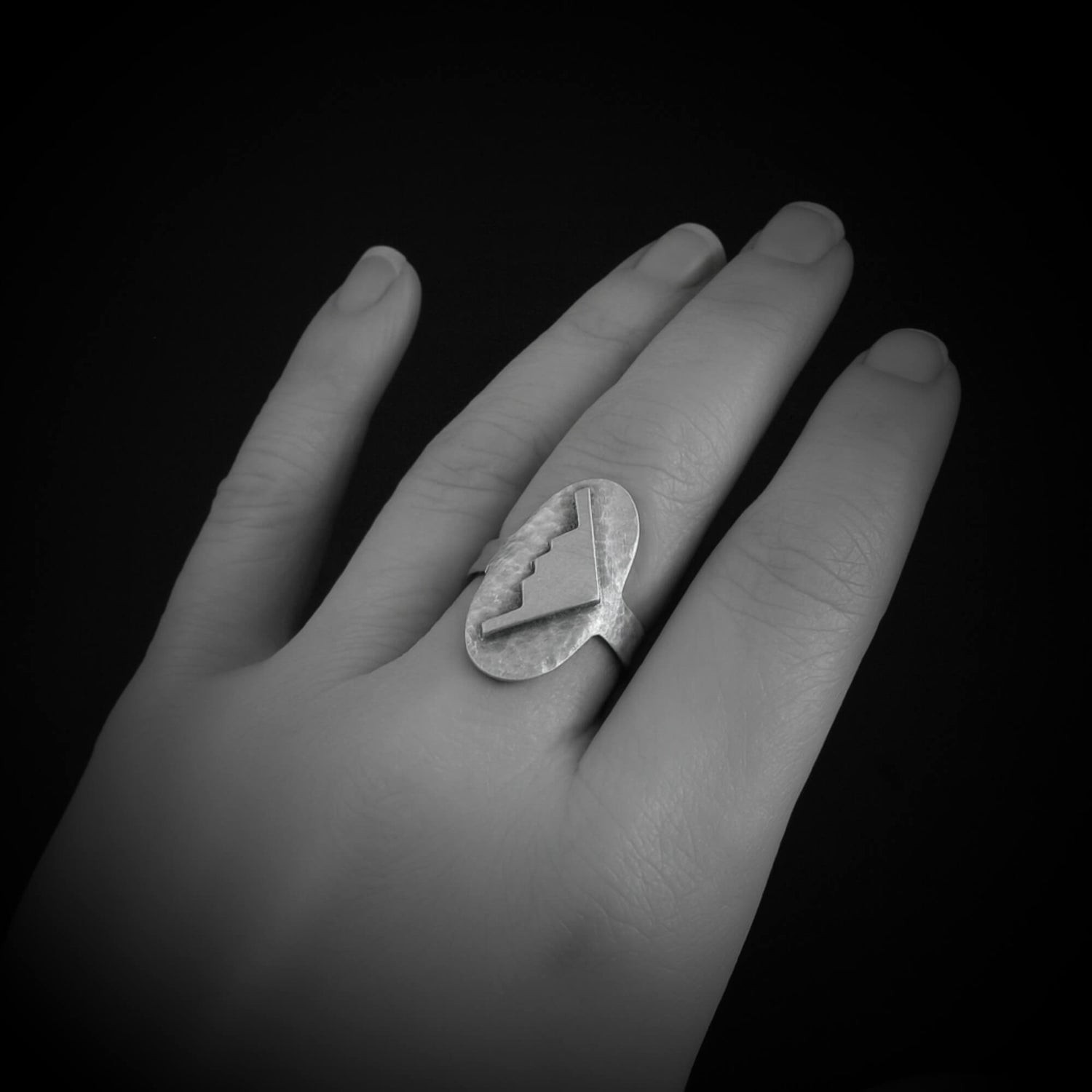 Hand wearing a silver ring with a B-2 Bomber Military Jet on a black background