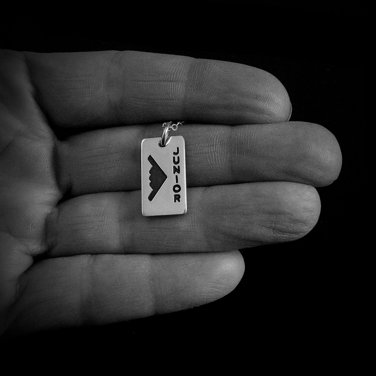 Sterling silver B‑2 Spirit bomber pendant necklace with “Junior” engraving – handmade aviation jewelry shown in hand for size