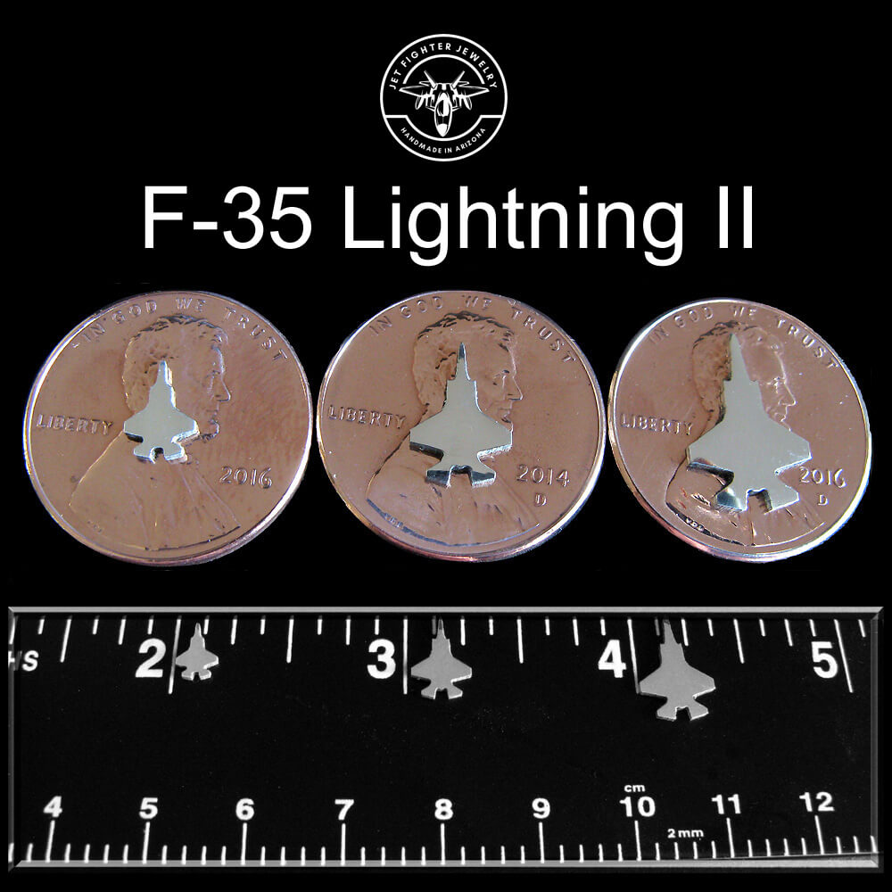 Three coins with F-35 Lightning II design on a black background with a ruler for scale.