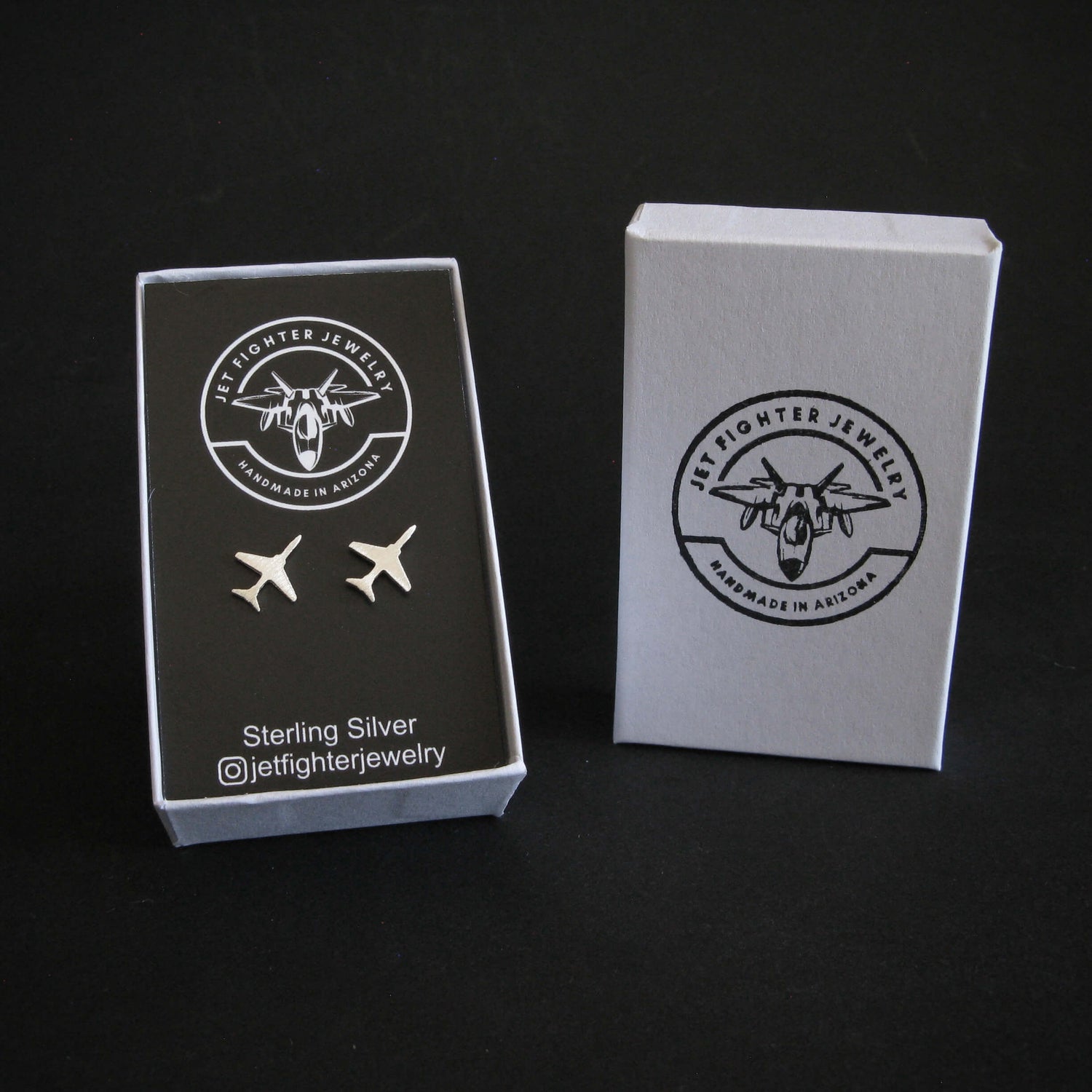 Jewelry box with airplane earrings and Jet fighter Jewelry branding on a black background