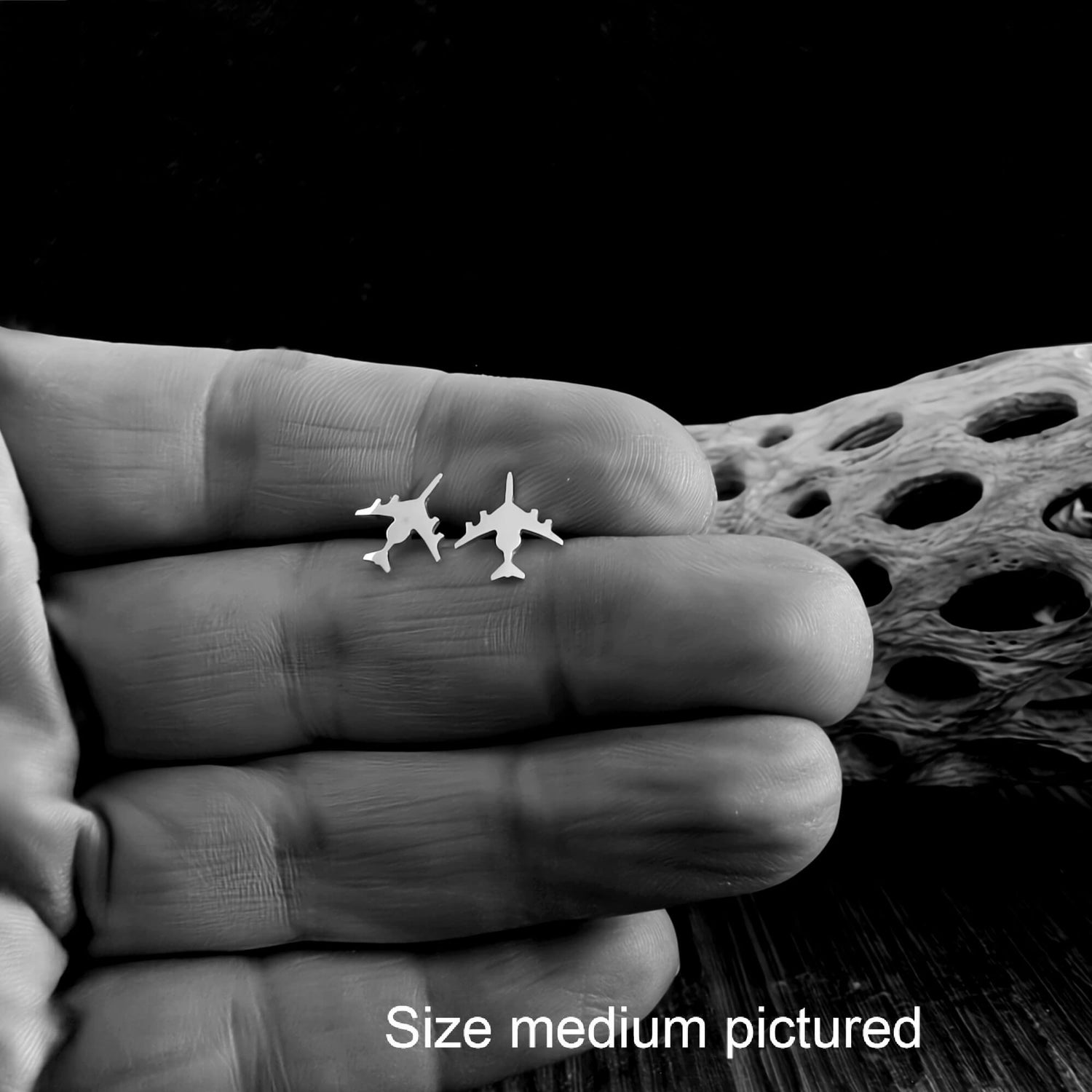 Silver E-3 Sentry Jet Fighter Stud Earrings held in a hand