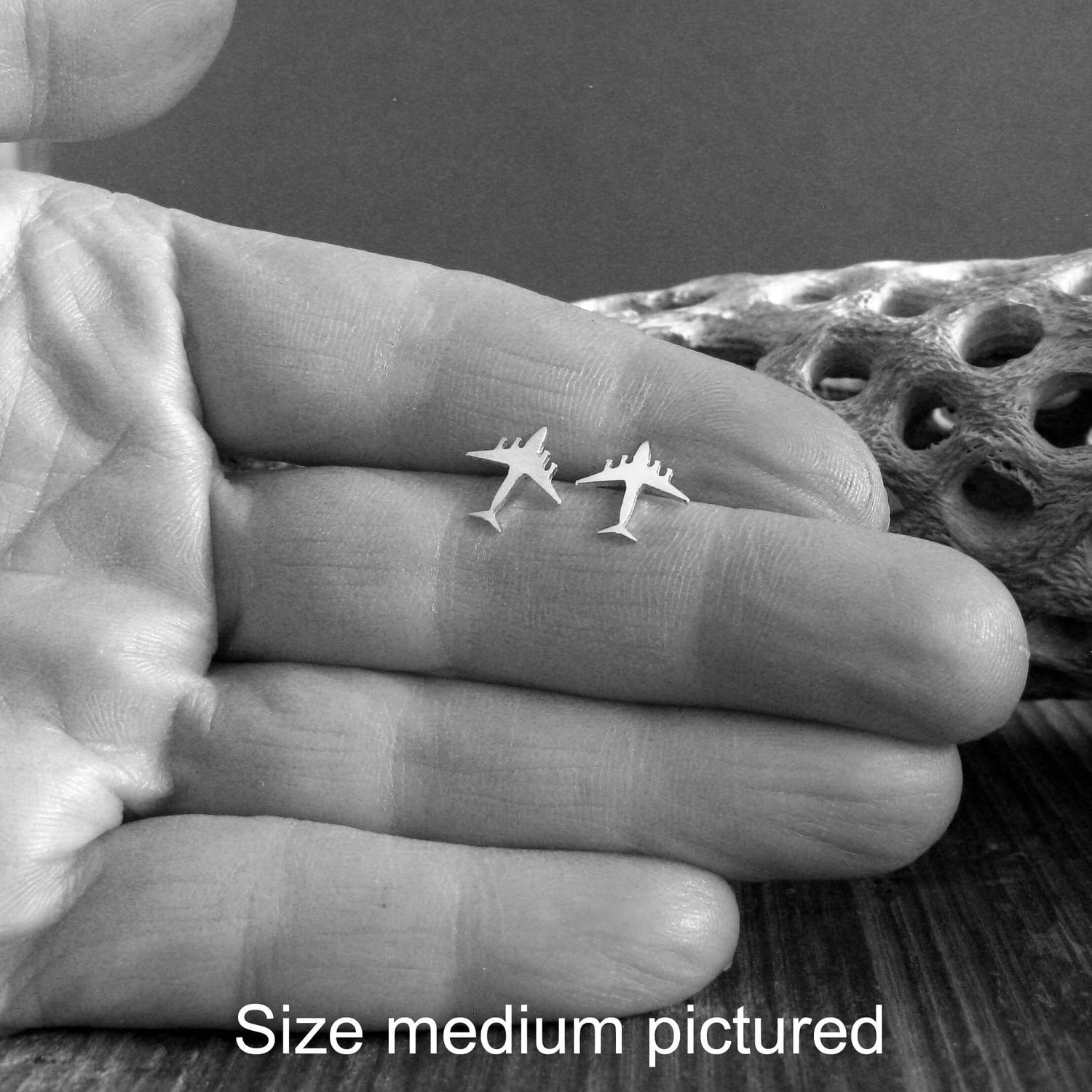 Pair of C-17 Military jet Fighter stud earrings held in a hand for size reference