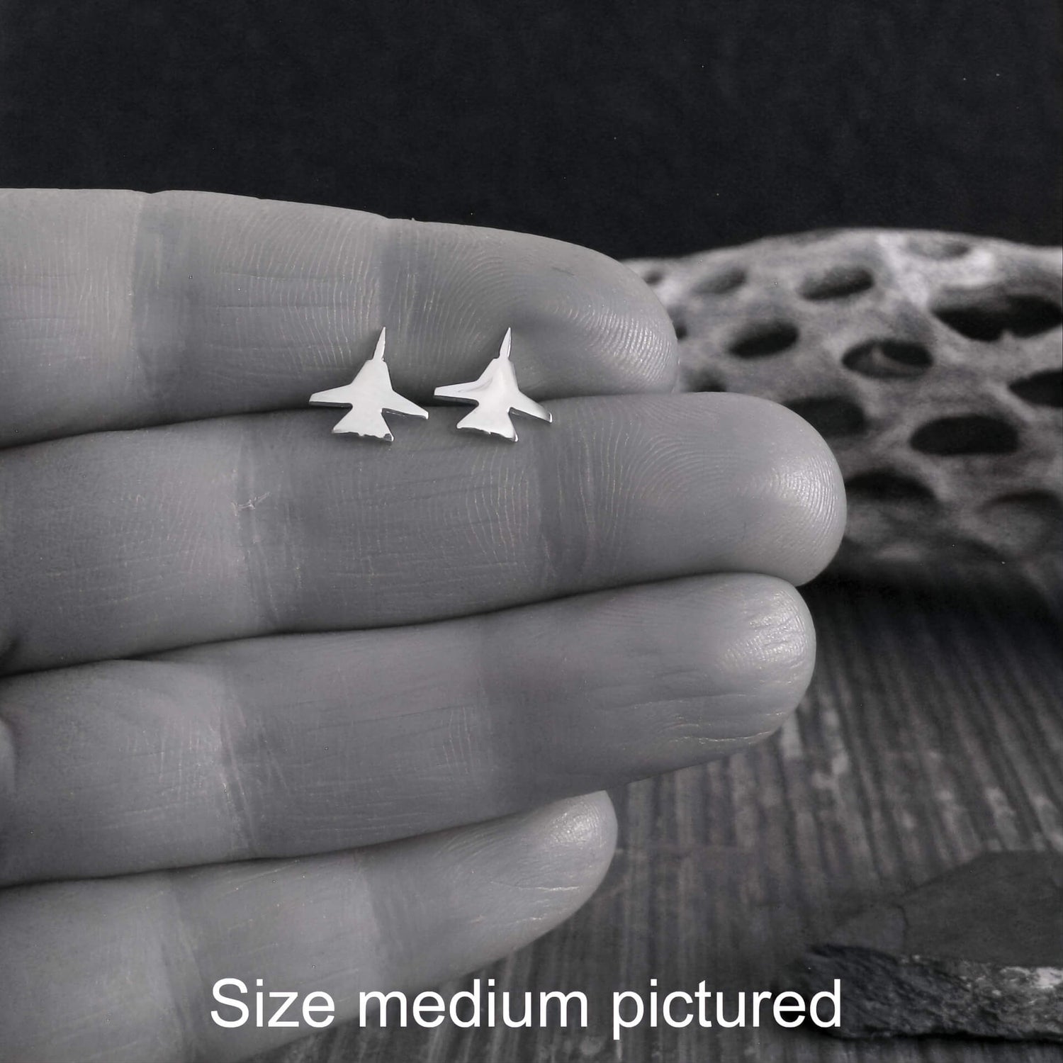 Pair of sterling silver F-14 Fighter Jet Stud earrings held in a hand close up