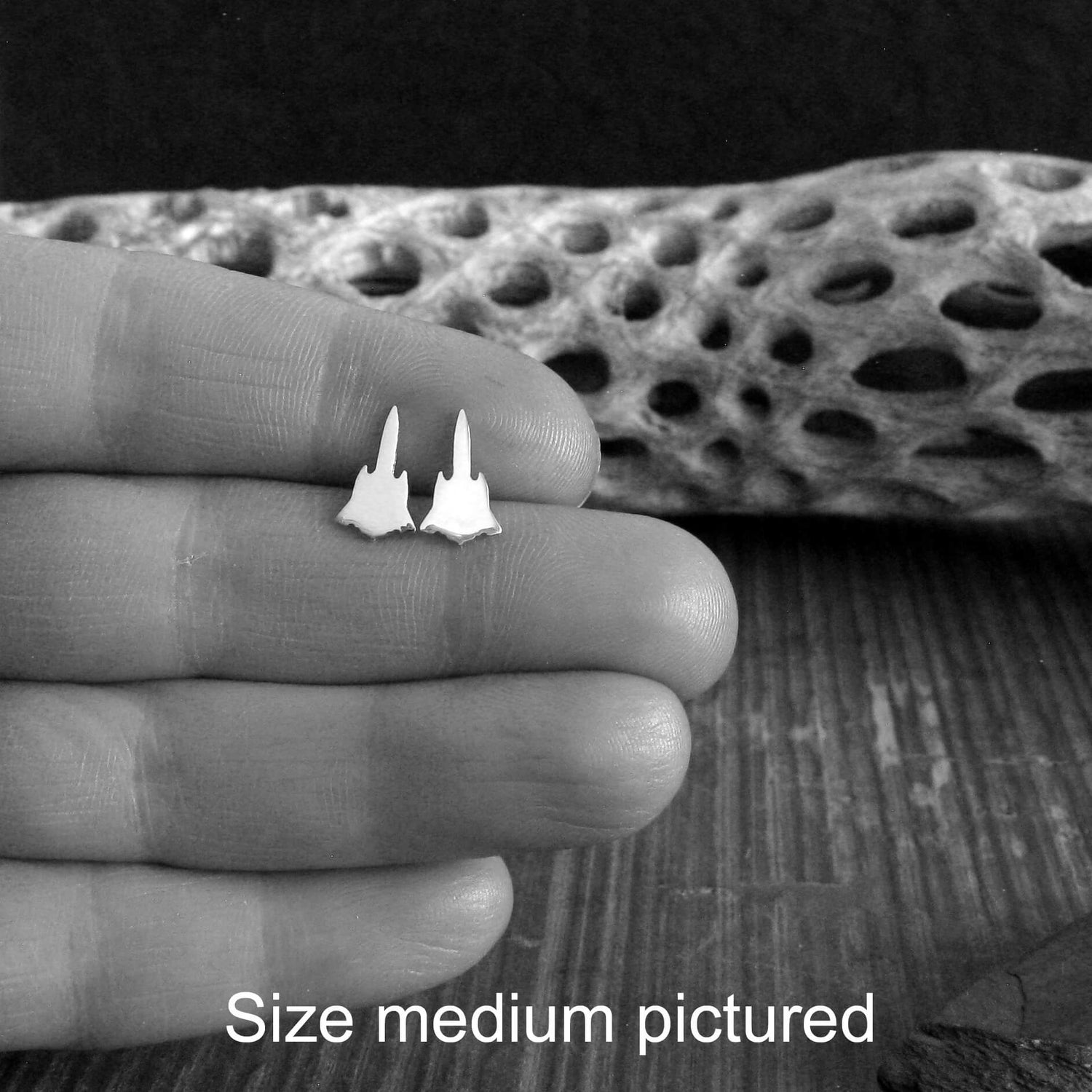 Pair of sterling silver SR-71 Military Jet Fighter stud earrings held in a hand between fingers close up