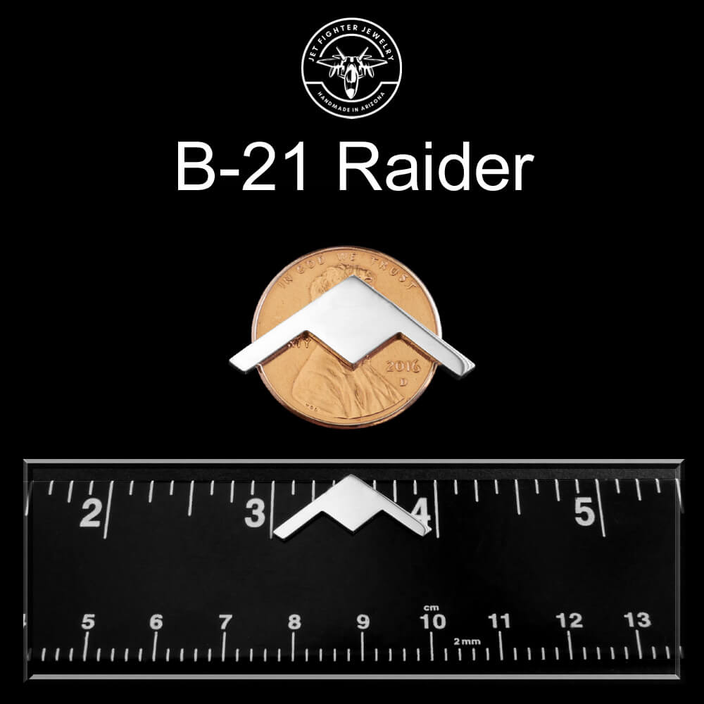 B-21 Raider cuff links on a coin with a ruler for scale against a black background