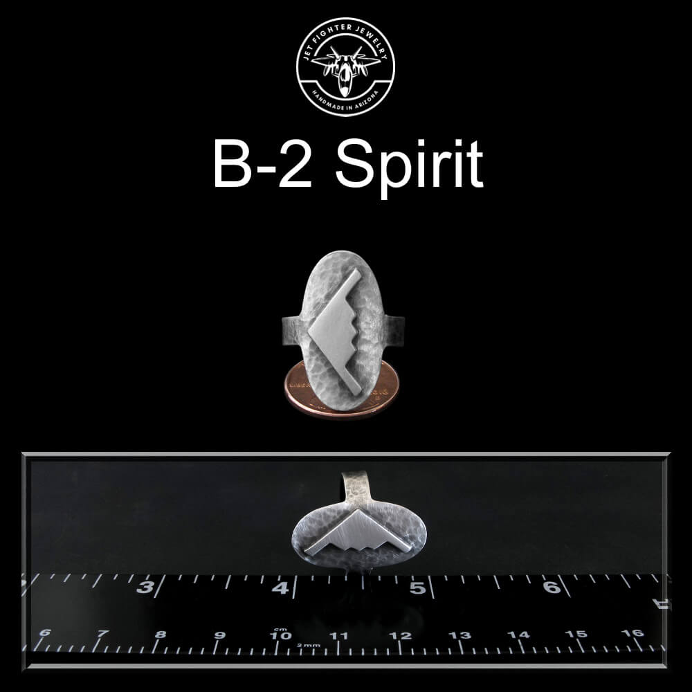 Ring with 'B-2 Spirit' design on a black background with a ruler for scale.