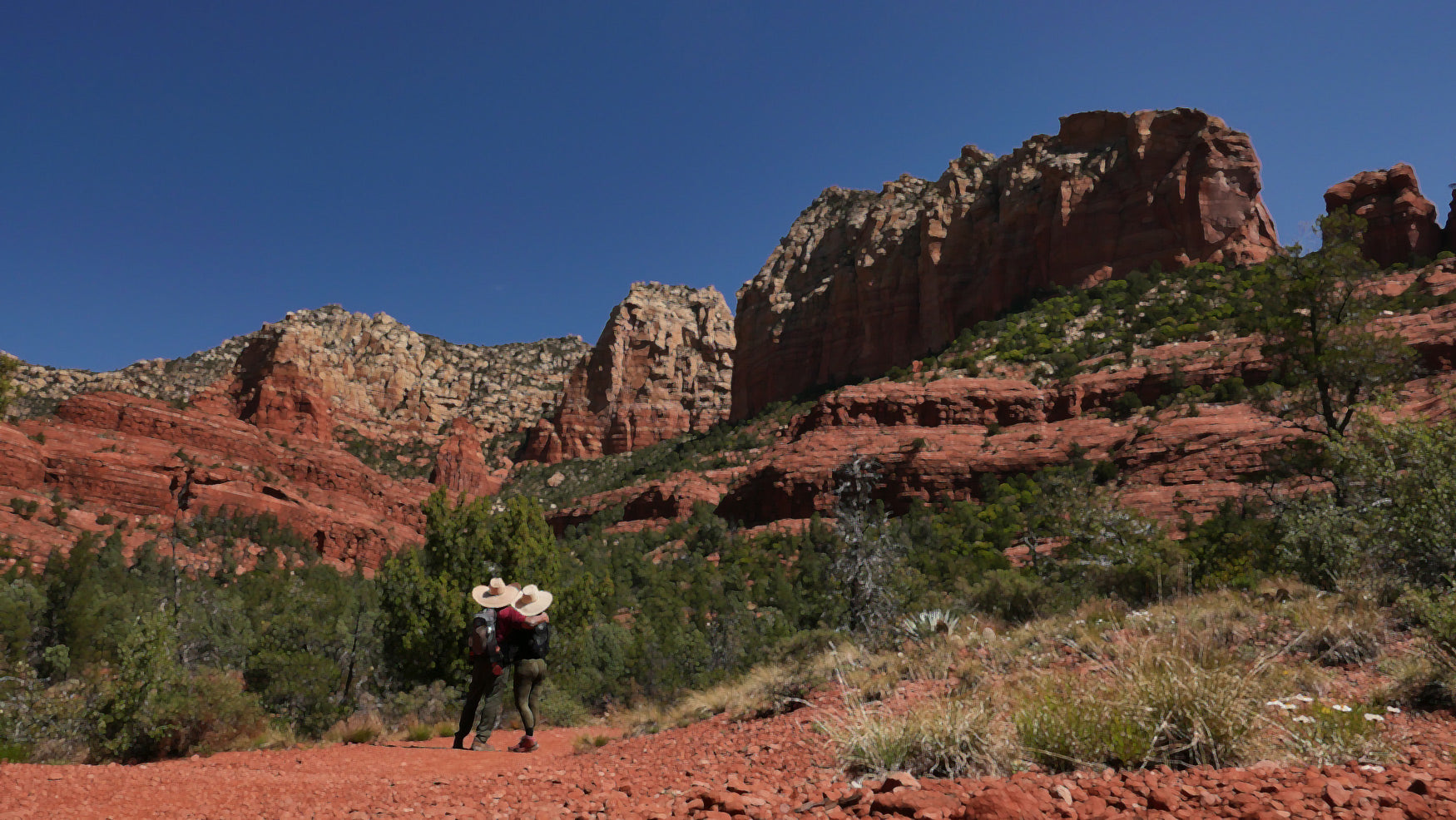Person hiking on a trail with red rock formations in the background