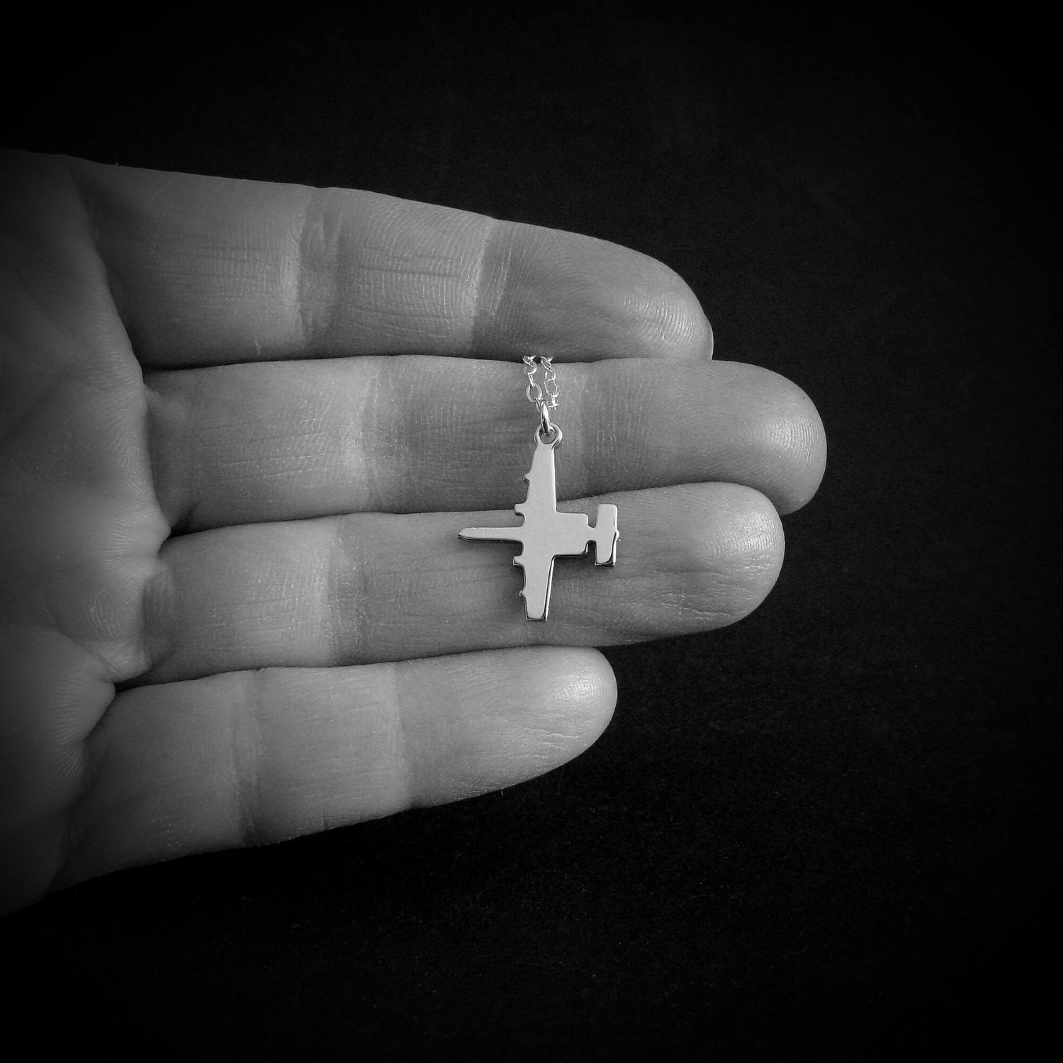 Sterling silver A-10 Warthog military airplane necklace in hand for scale