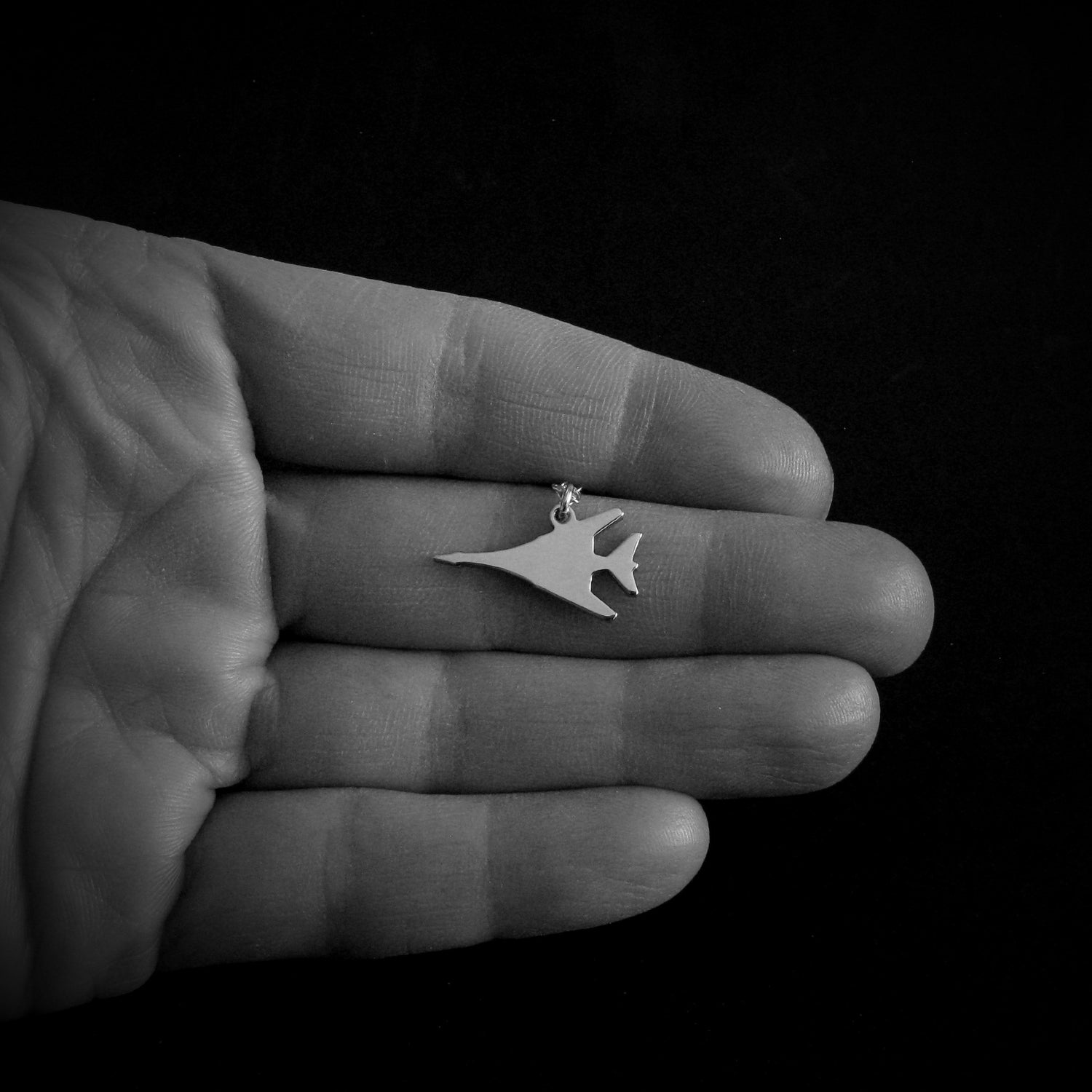 Sterling silver B-1 Lancer bomber pendant necklace shown in hand – handmade aviation jewelry