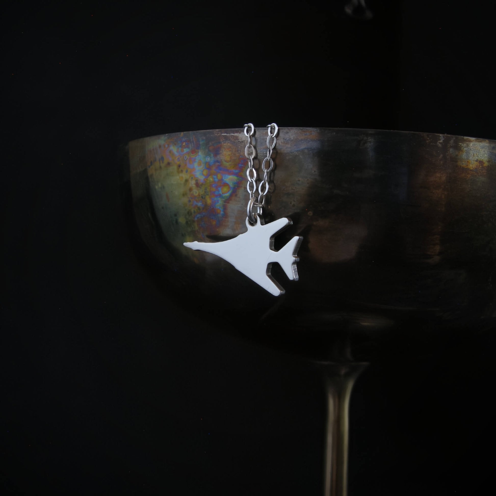 Sterling silver B-1 Lancer bomber pendant necklace displayed on wine goblet – handcrafted military aviation jewelry 