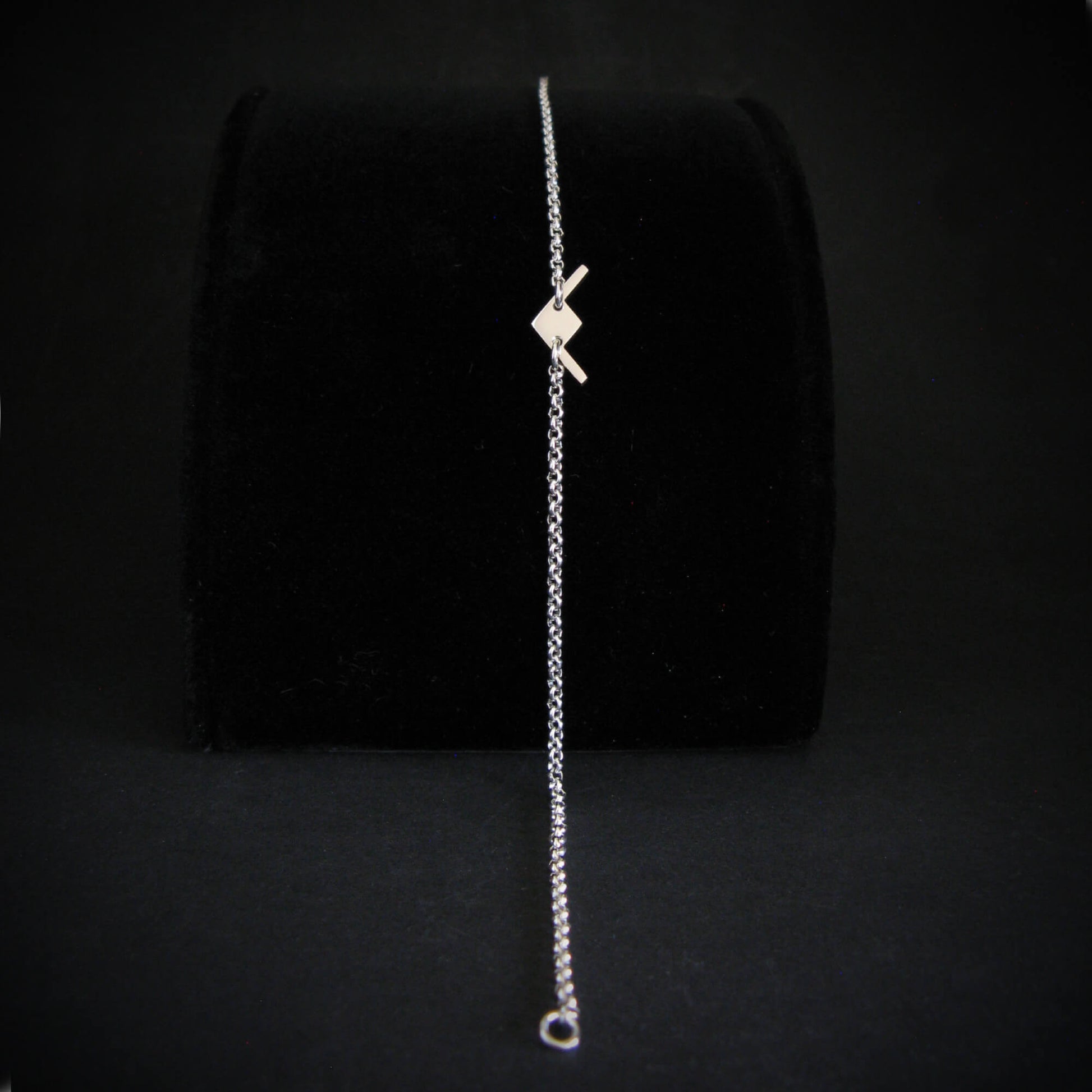Sterling silver B-21 Raider dainty bracelet displayed on velvet stand