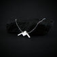 Handmade sterling silver B-21 Raider bomber jet necklace displayed on dark rock