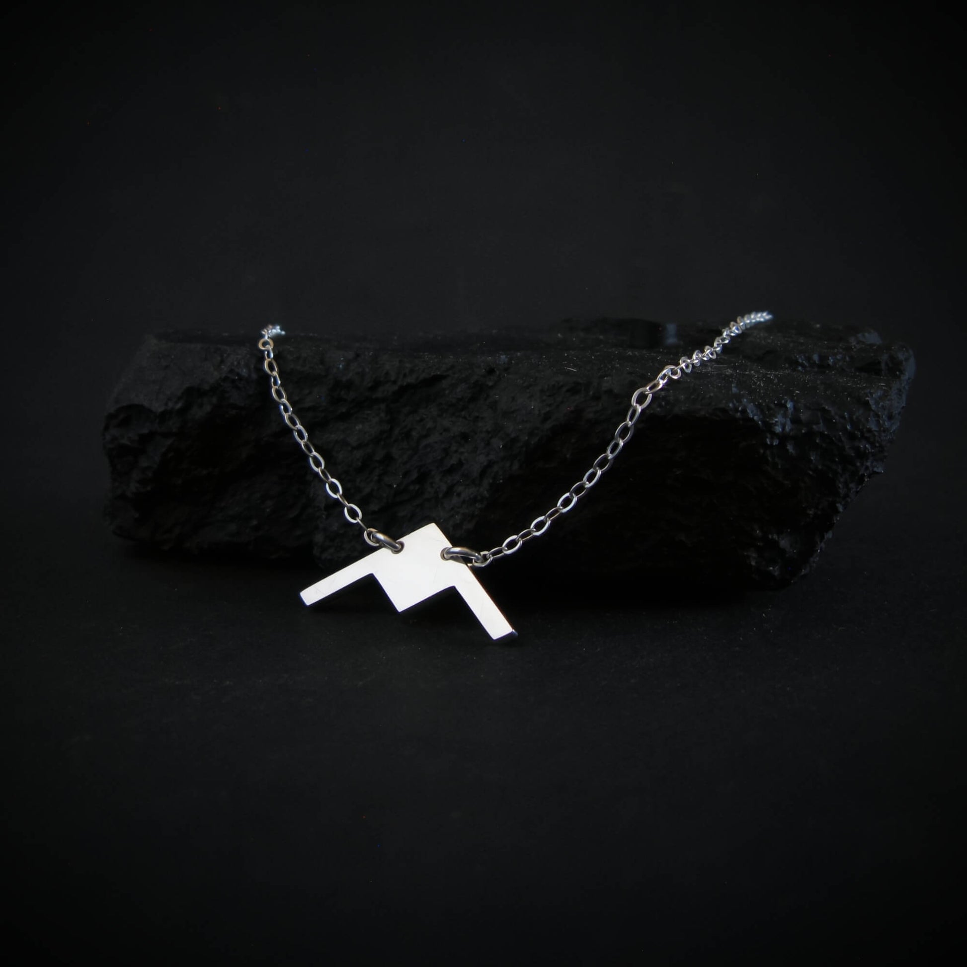 Handmade sterling silver B-21 Raider bomber jet necklace displayed on dark rock