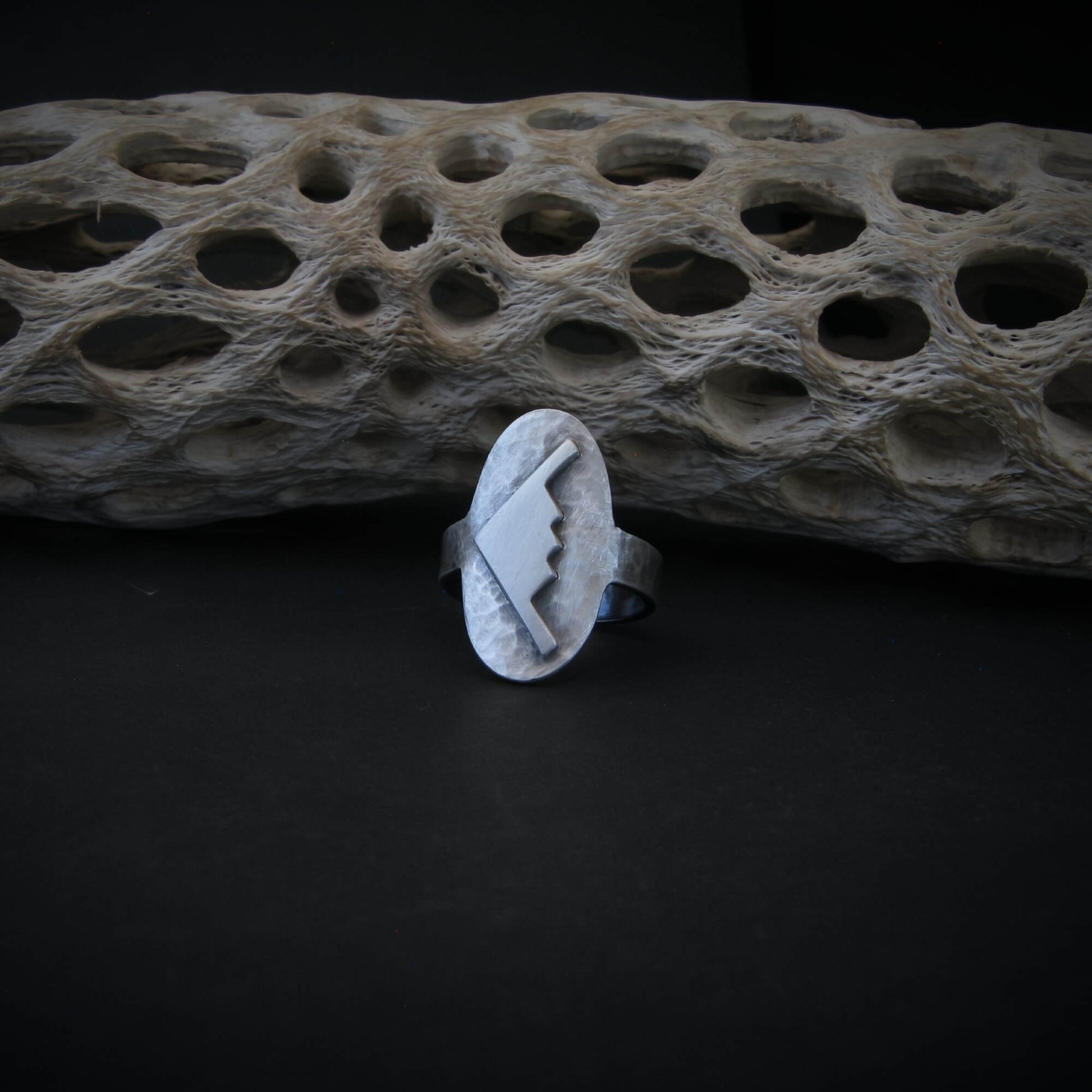 Hammered silver oval ring with a raised B-2 Bomber Military Aviation Jet on a black background with driftwood