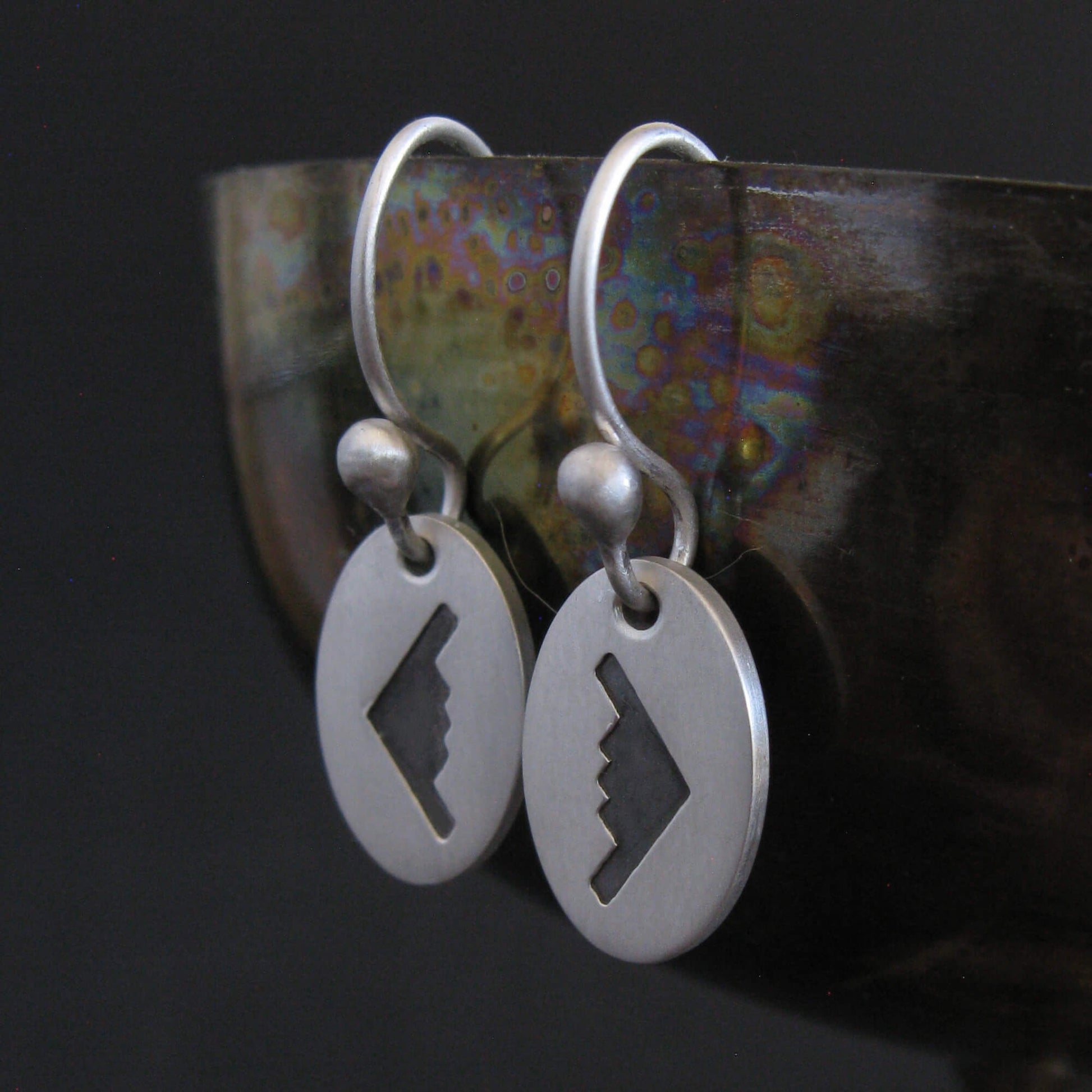 Satin sterling silver B‑2 Spirit bomber airplane dangle earrings displayed on artistic background – handmade military aviation jewelry