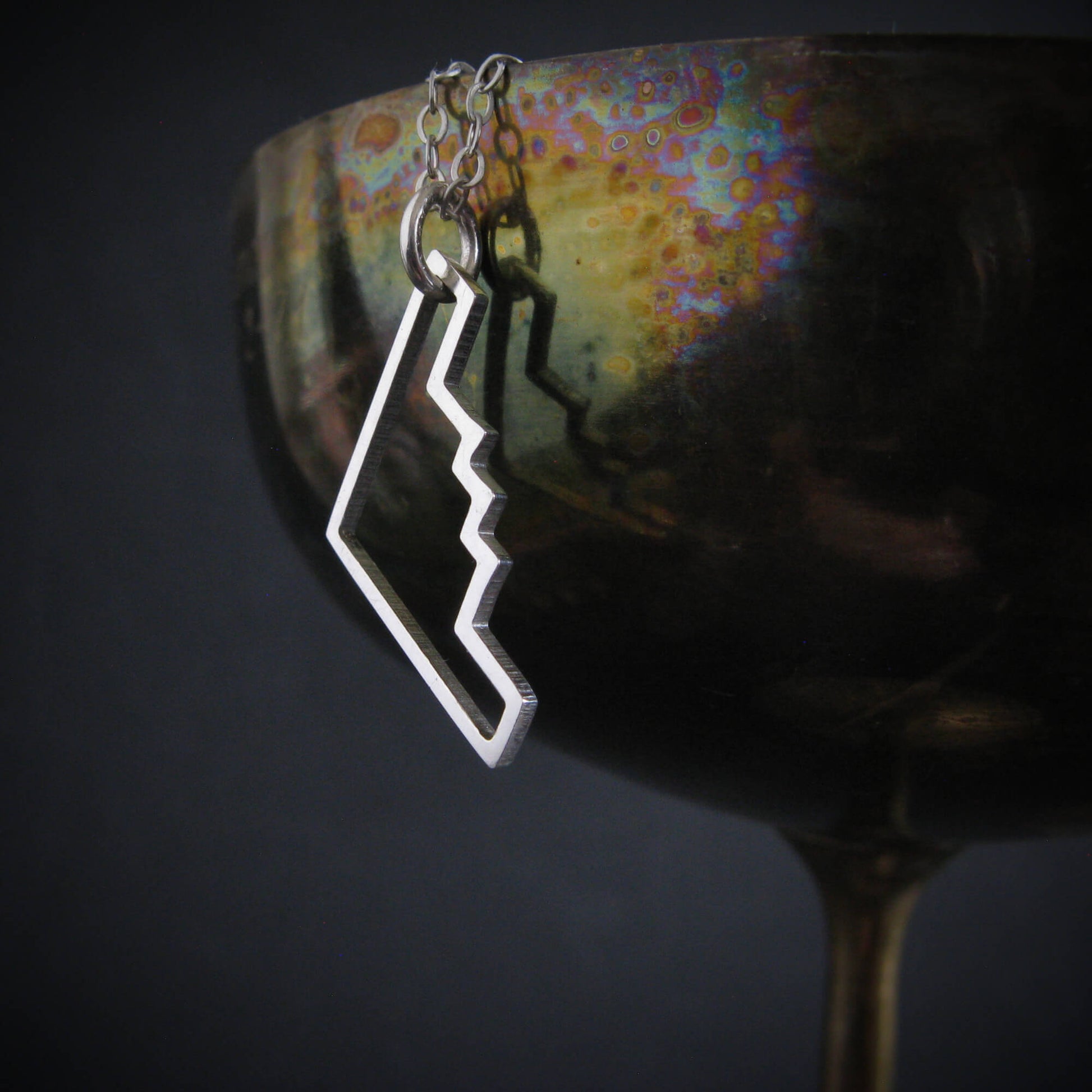 Sterling silver B‑2 Spirit bomber airplane outline pendant necklace hanging on artistic background – handmade aviation jewelry