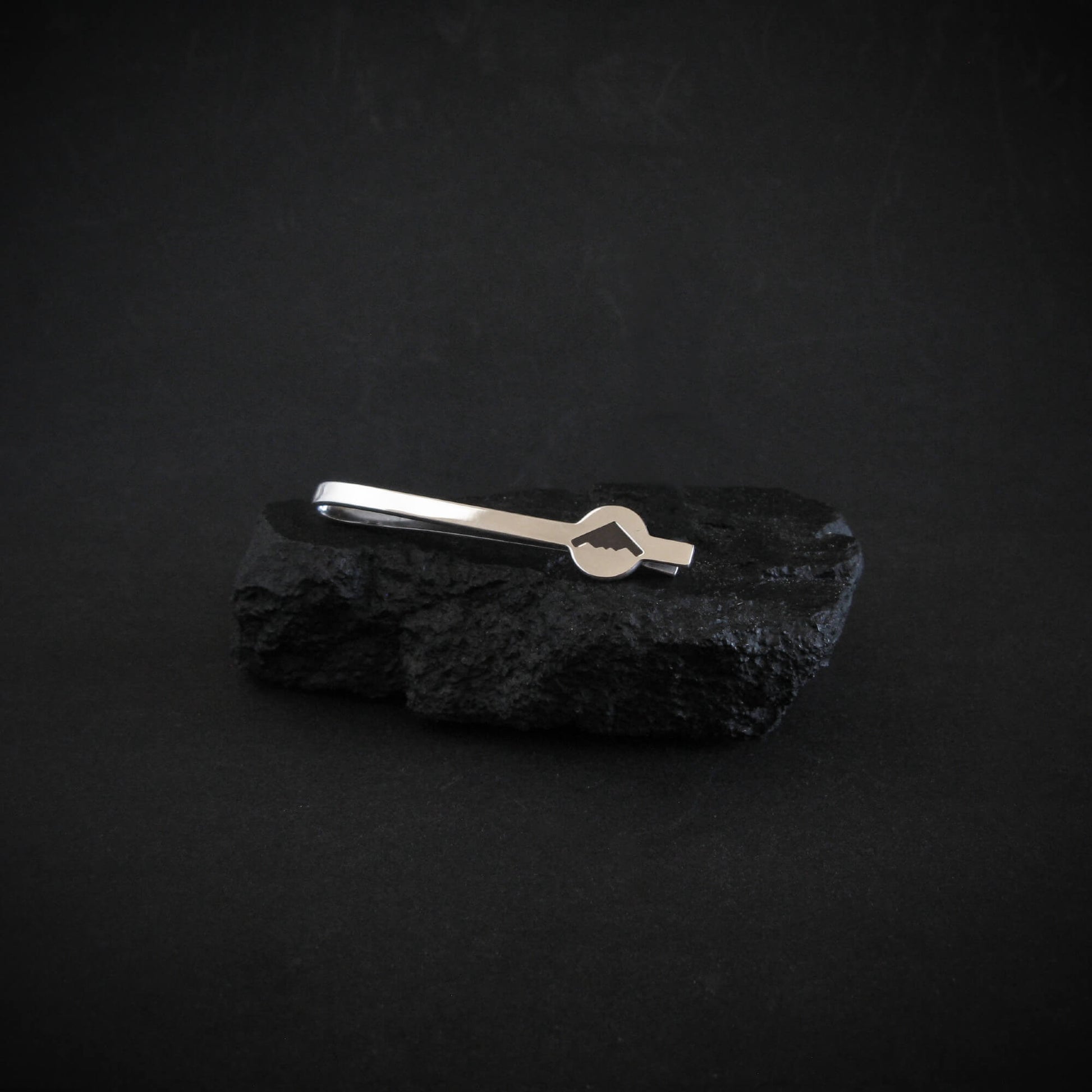Sterling silver B-2 Spirit Bomber tie bar displayed on black volcanic stone with engraved aircraft detail