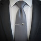 Gray tie with a silver B2 Bomber Military Jet tie clip on a white shirt and black suit.