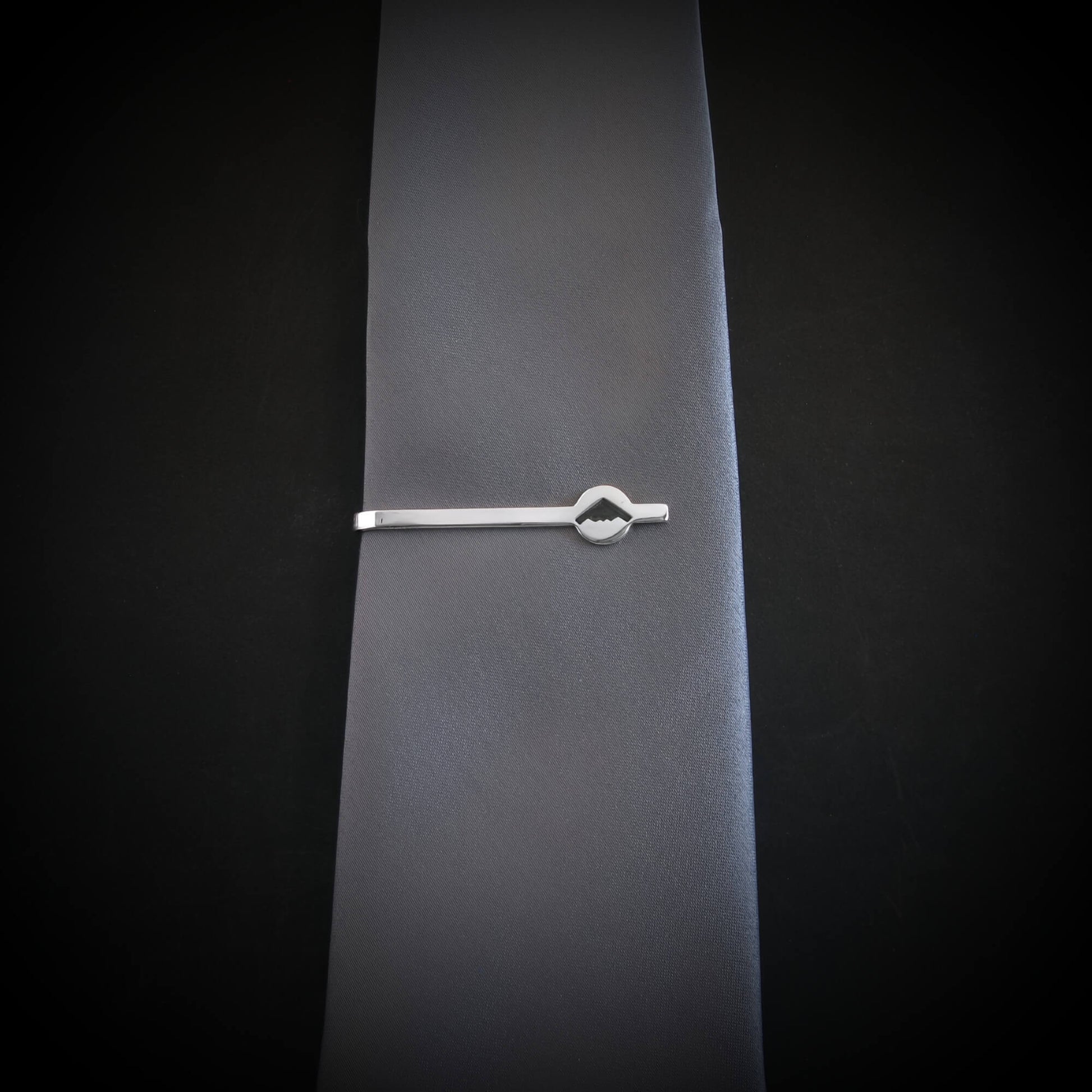 Sterling silver B-2 Spirit Bomber tie clip attached to gray necktie, showcasing sleek engraved design