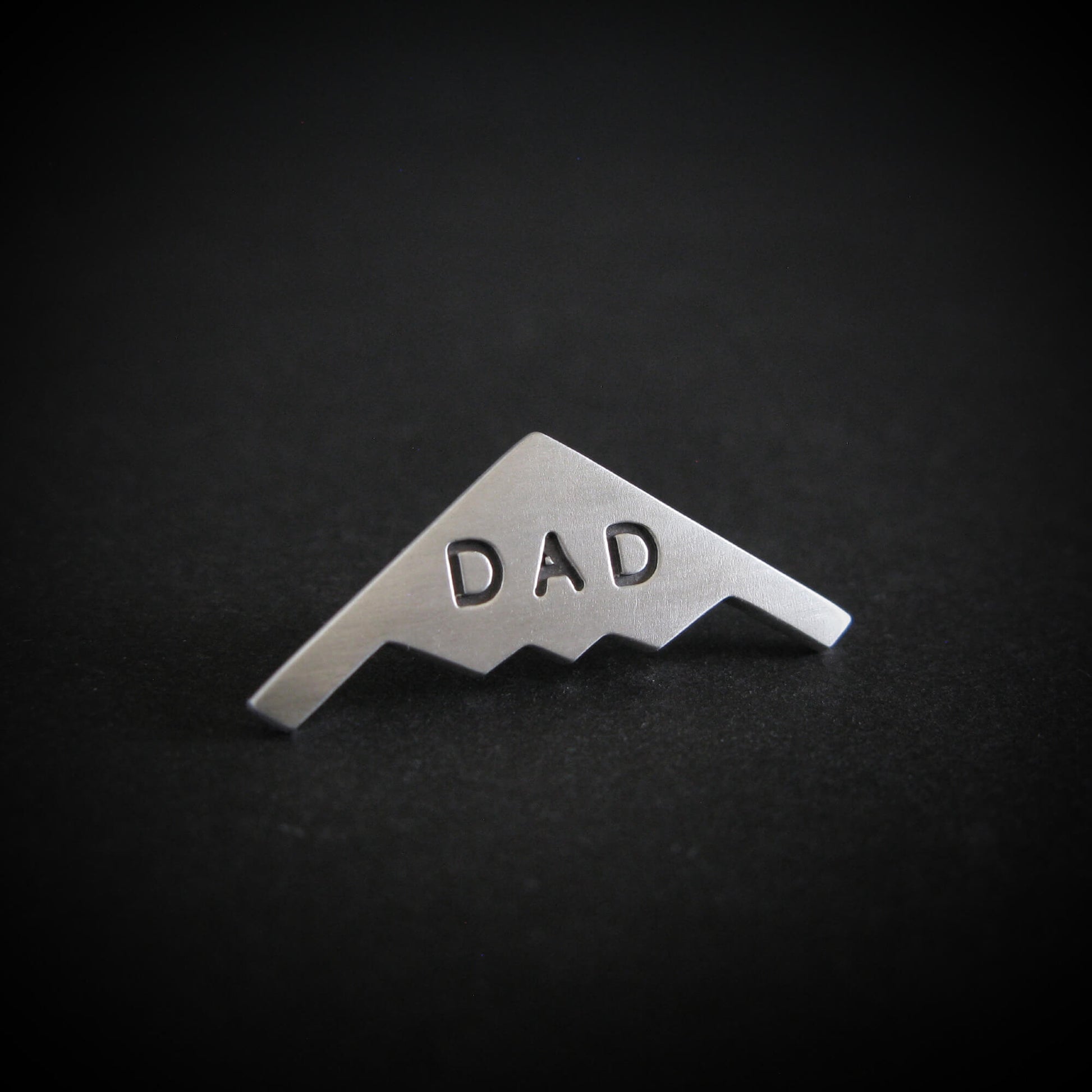 Silver Engraved "DAD" B-2 Spirit Bomber military fighter jet airplane tie tack on a black background