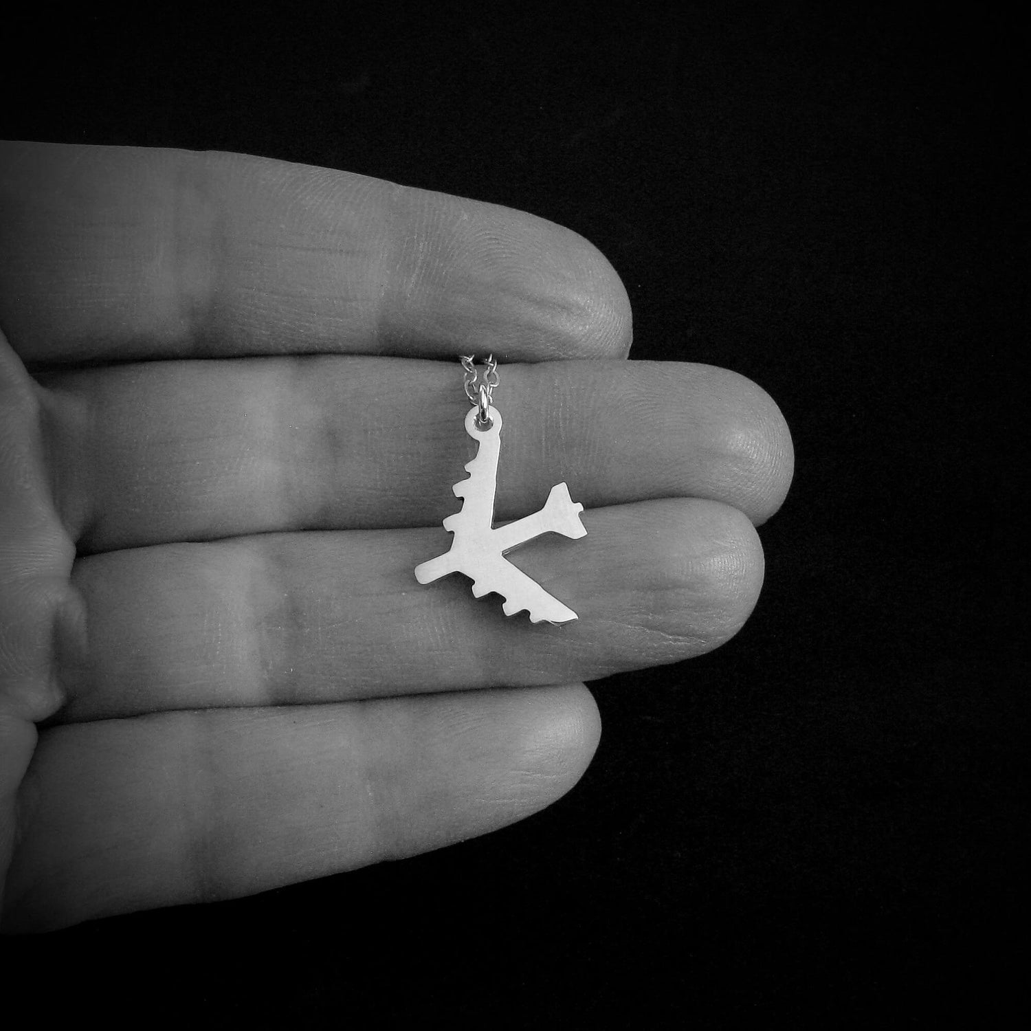 B-52 Bomber Military Jet Silver Pendant necklace held in a hand