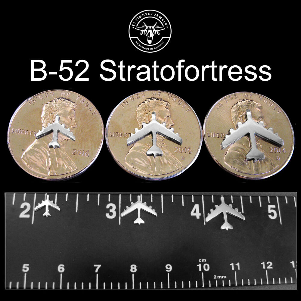 Three coins with B-52 Stratofortress stud earring airplane designs on a black background with a ruler for scale.
