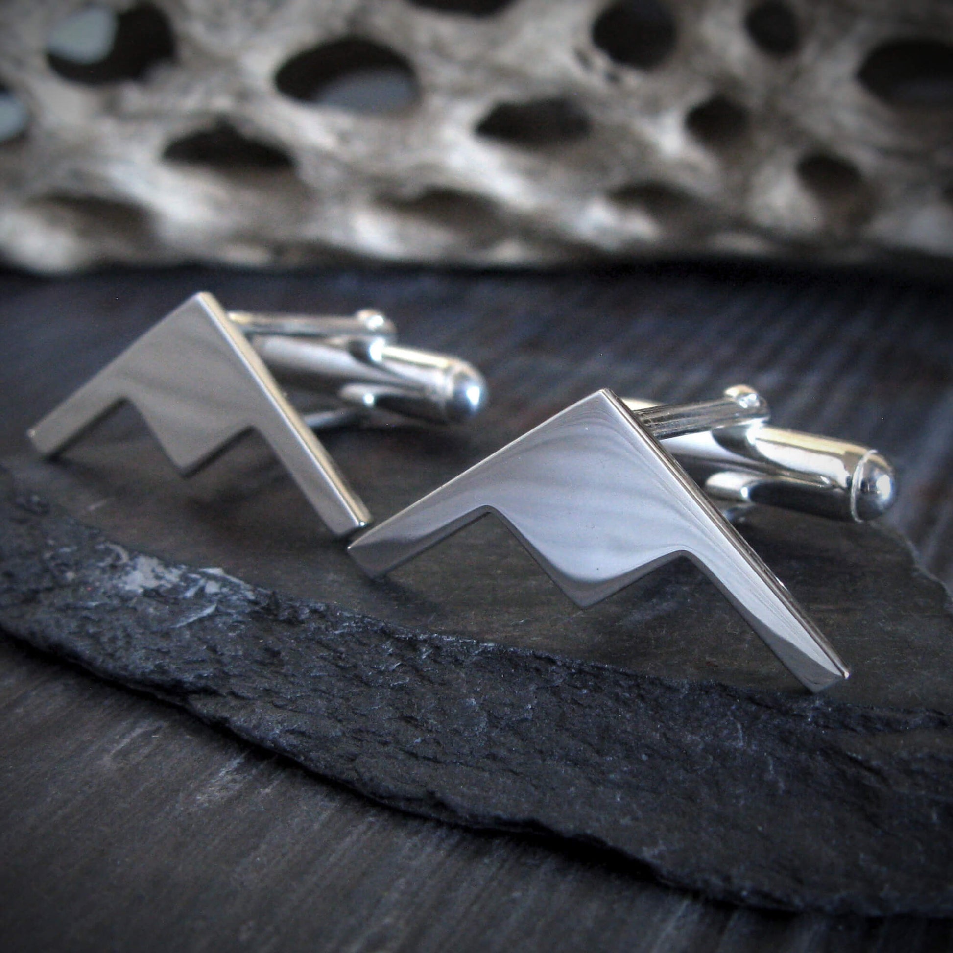 Aviation-inspired B-21 Raider bomber jet cuff links on textured stone surface