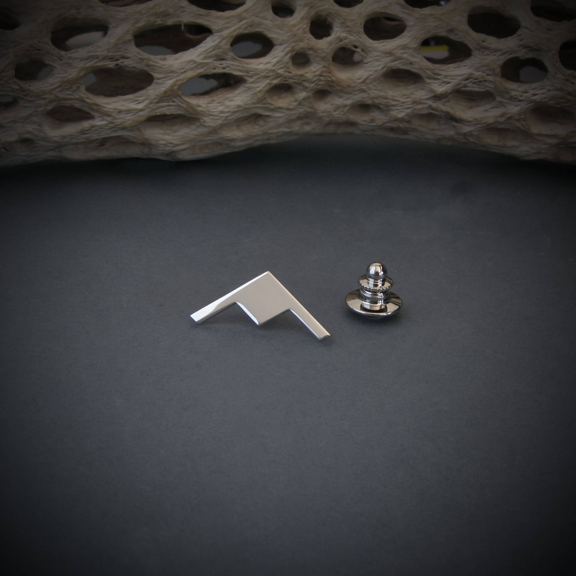 Silver B-21 Raider Bomber Jet Silhouette Tie Tack and locking back on a dark background