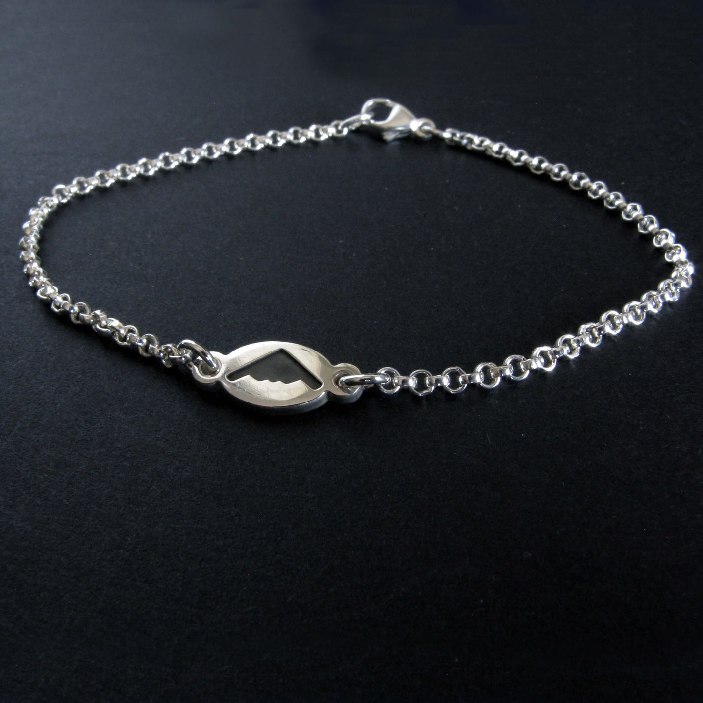 Dainty Sterling Silver bracelet with a B-2 Spirit silhouette charm on a black background