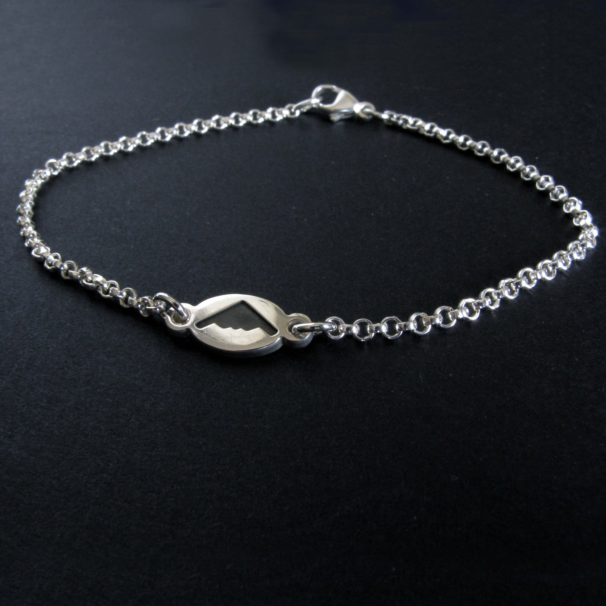 Dainty Sterling Silver bracelet with a B-2 Spirit silhouette charm on a black background
