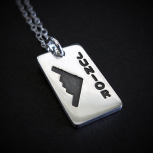 Close‑up of sterling silver B‑2 Spirit stealth bomber pendant necklace with “Junior” engraving – artisan aviation jewelry