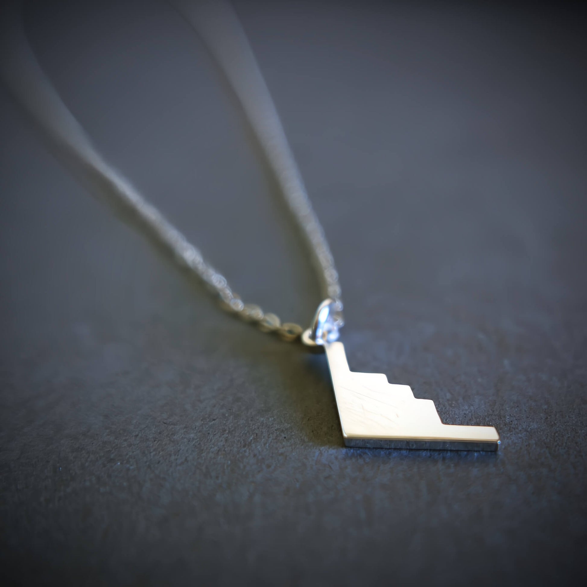Silver B-2 Spirit Bomber Military Jet Pendant necklace on a dark background