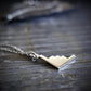 Silver B-2 Spirit Bomber Military Jet Pendant necklace on a stone surface