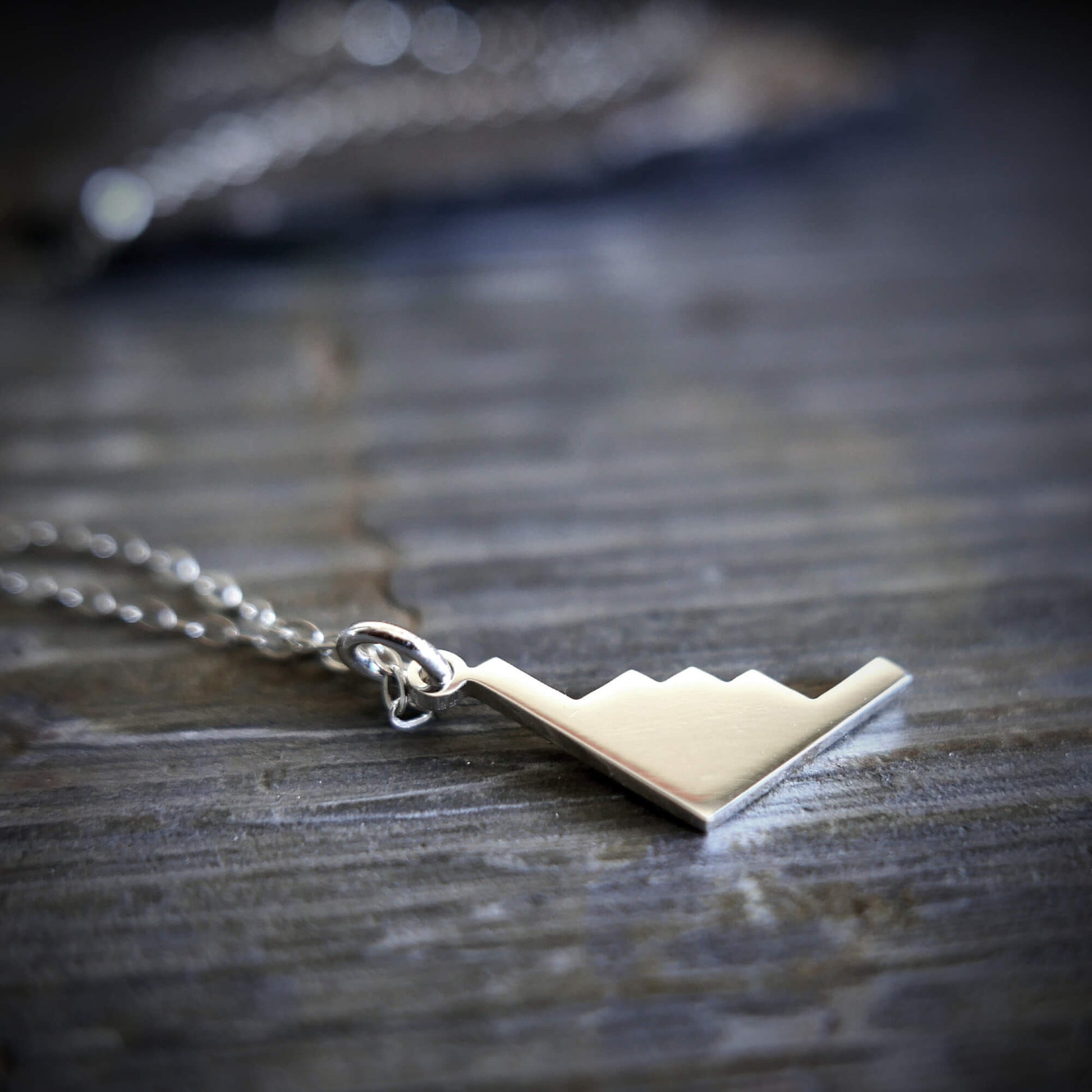 Silver B-2 Spirit Bomber Military Jet Pendant necklace on a stone surface