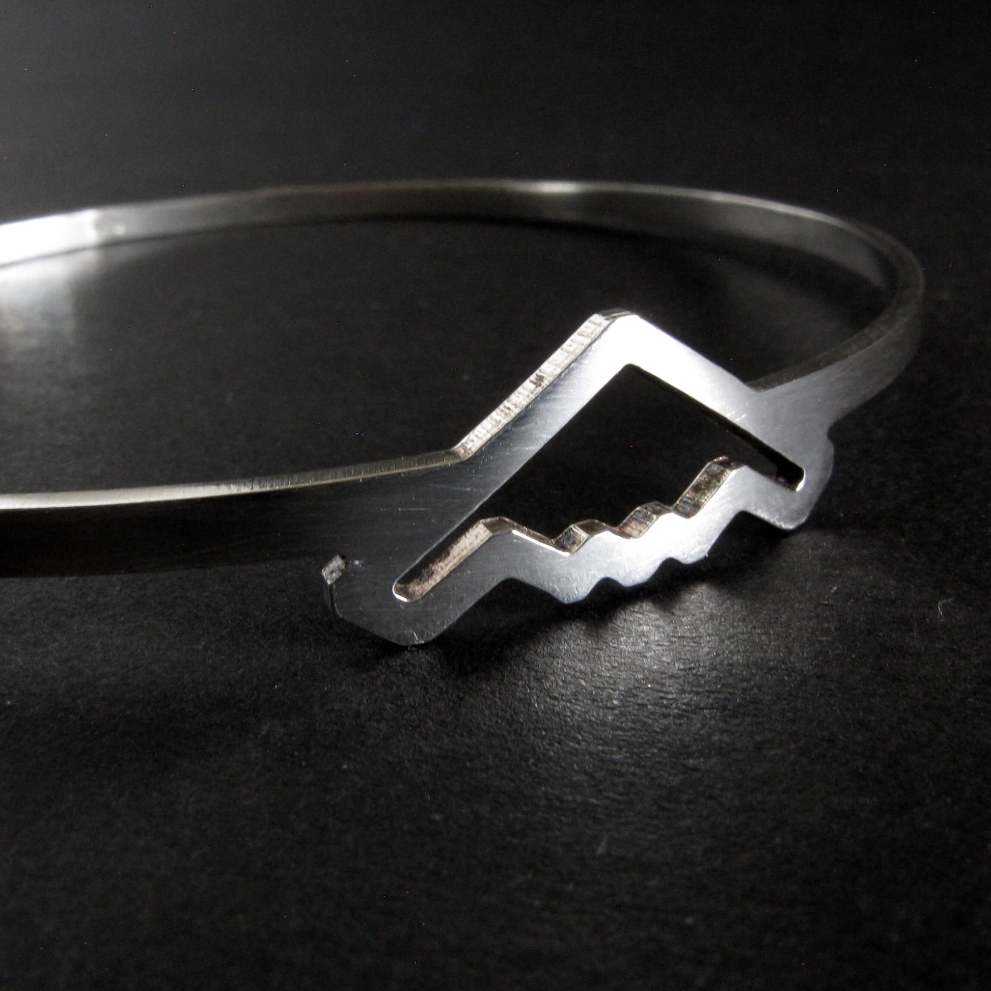Close up of a Silver bangle bracelet with B-2 Bomber Jet on a dark background