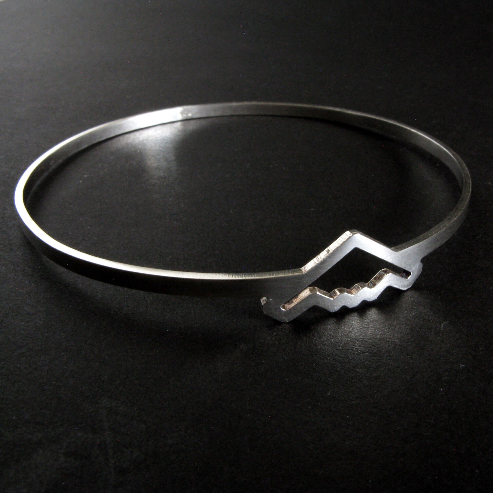 Silver bangle bracelet with B-2 Bomber Military Jet on a dark background