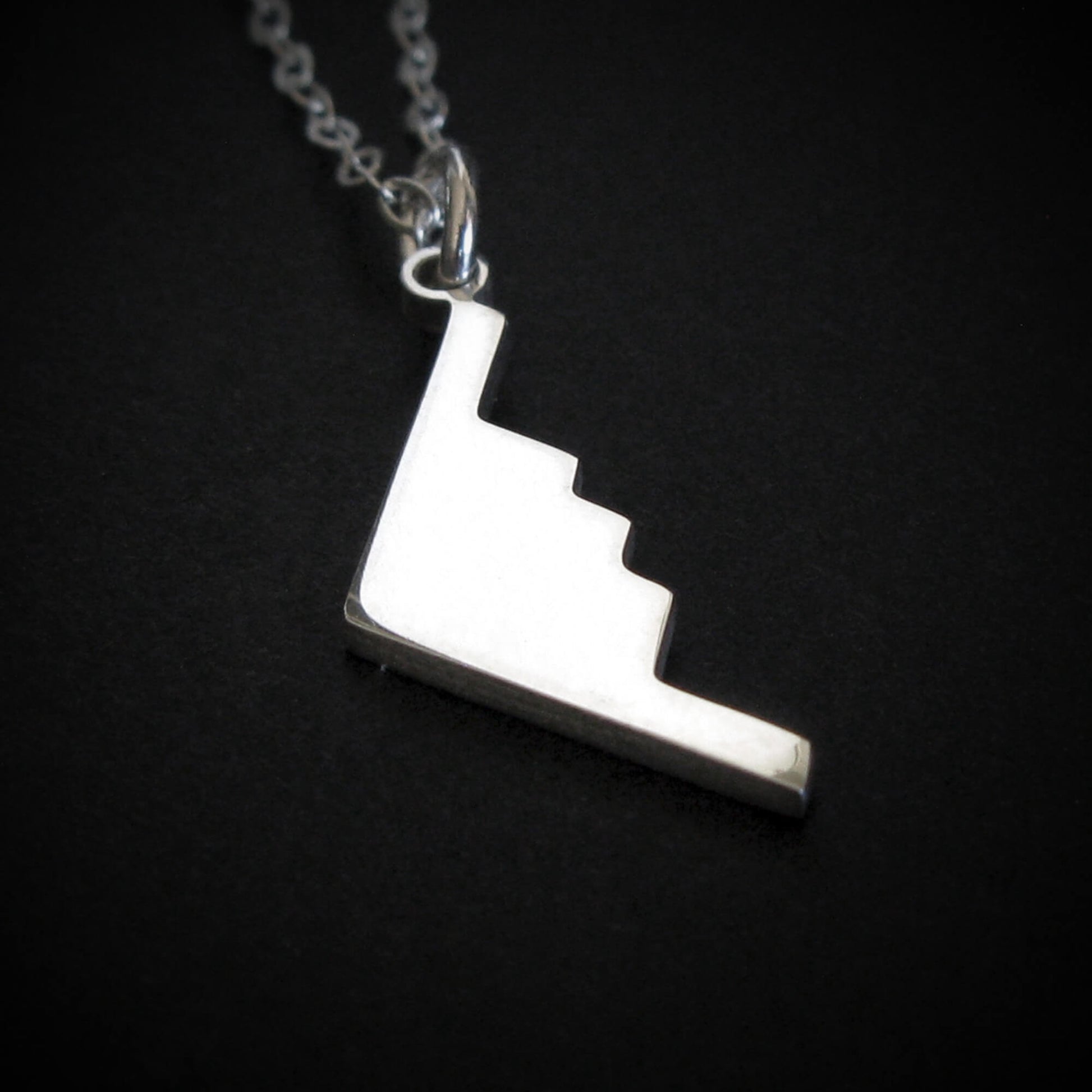 Silver B-2 Spirit Bomber Military Jet Pendant necklace on a dark background