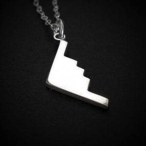 Silver B-2 Spirit Bomber Military Jet Pendant necklace on a dark background