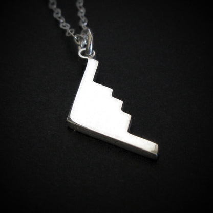 Silver B-2 Spirit Bomber Military Jet Pendant necklace on a dark background