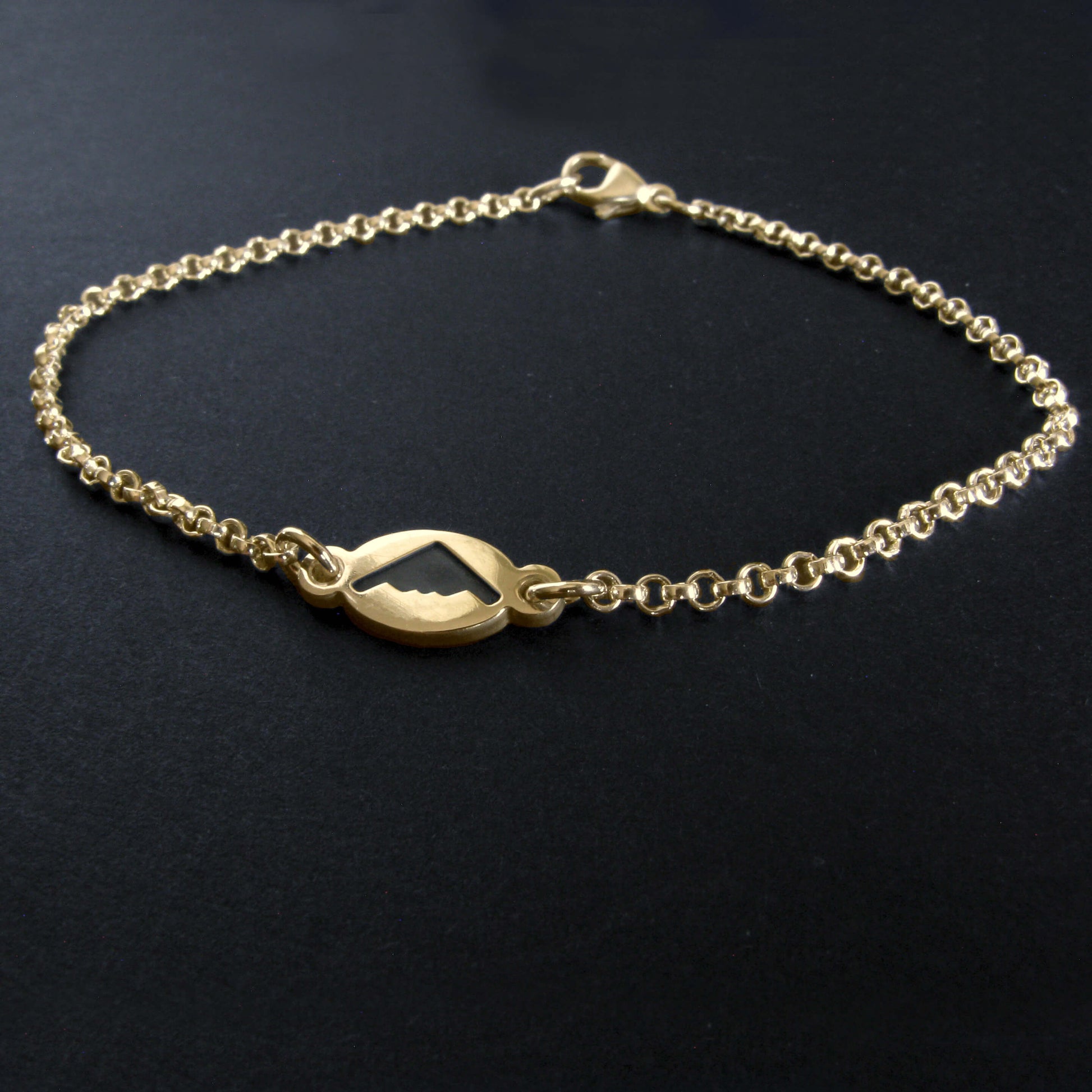 Gold B2 Spirit Bomber charm bracelet on a dark background