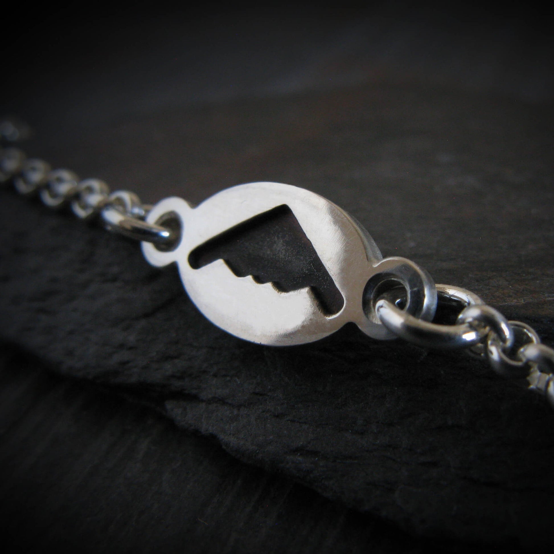 B-2 Sterling Silver dainty charm bracelet on a dark rock