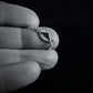 Close-up of a hand holding a delicate  B-2 jet sterling silver necklace against a black background