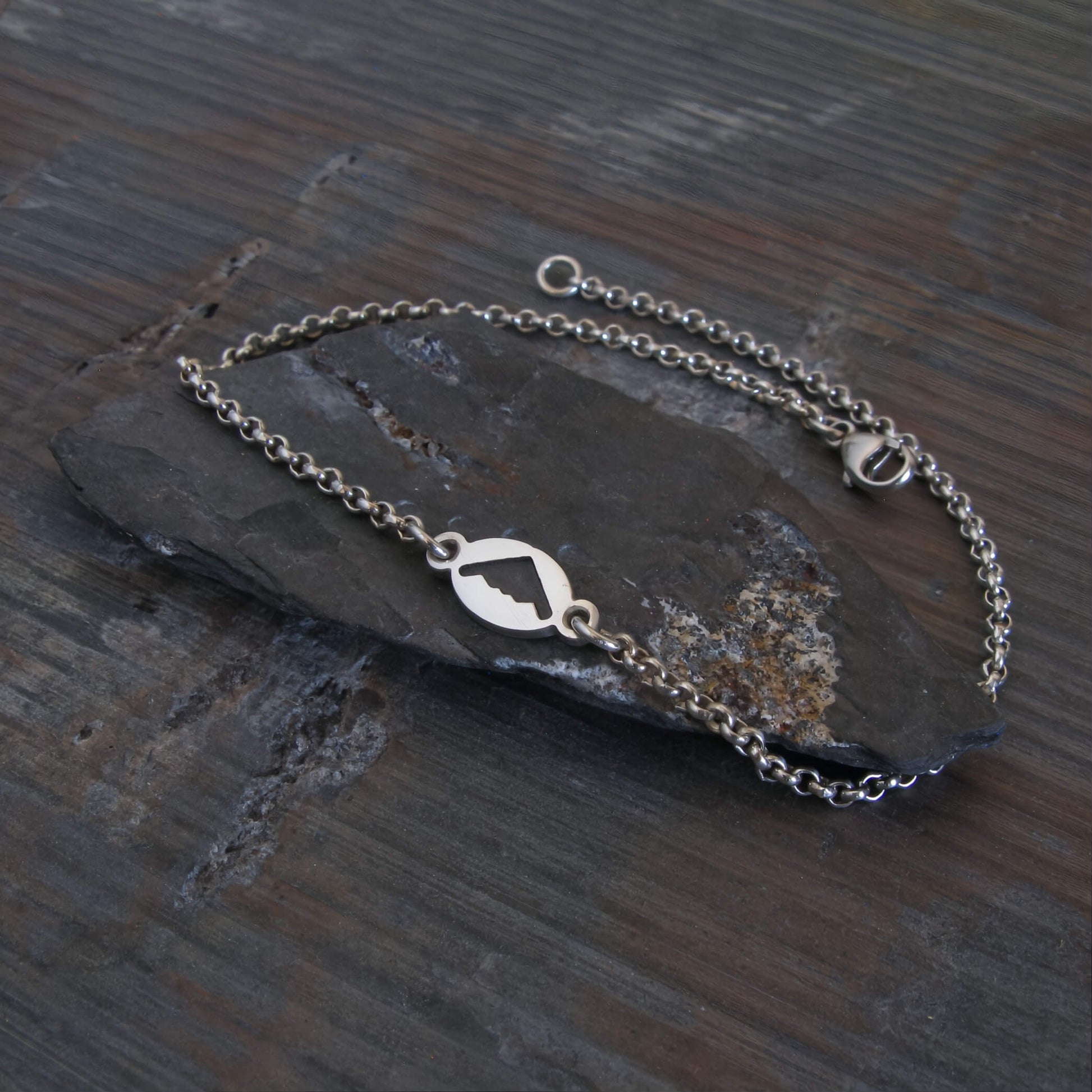Sterling Silver bracelet with a B2 Spirit silhouette charm on a dark stone surface