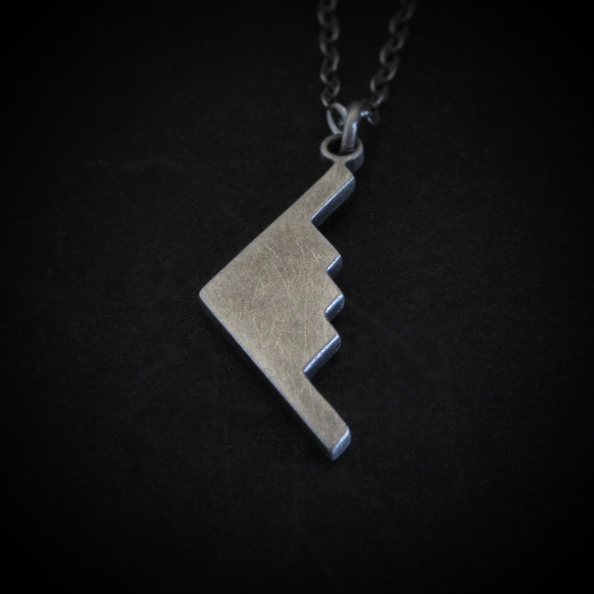 Antiqued Silver B-2 Spirit Bomber Military Jet necklace pendant on a dark background