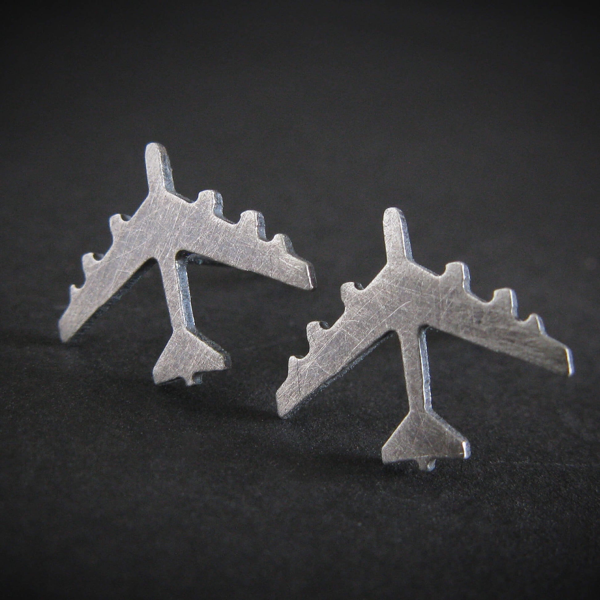 Antiqued Silver B-52 military Fighter Jet airplane shaped stud earrings with a dark background