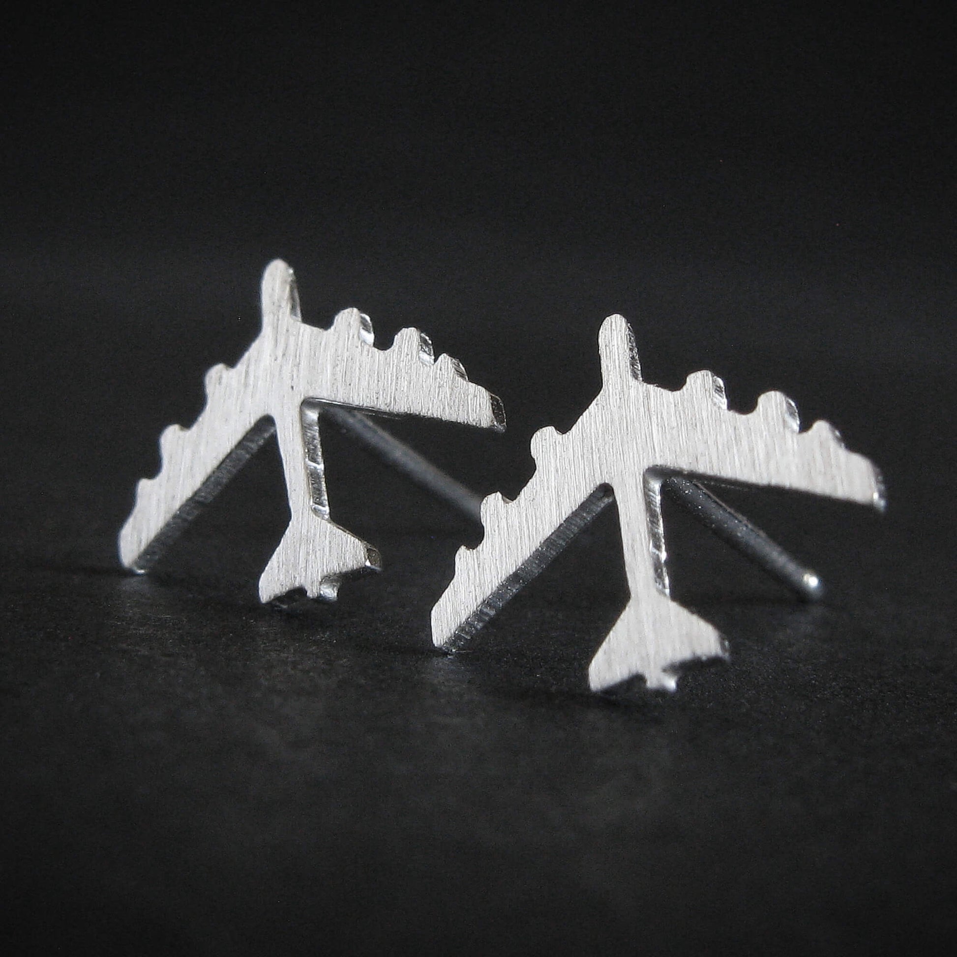 Brushed Silver B-52 military Fighter Jet airplane shaped earrings with a dark background