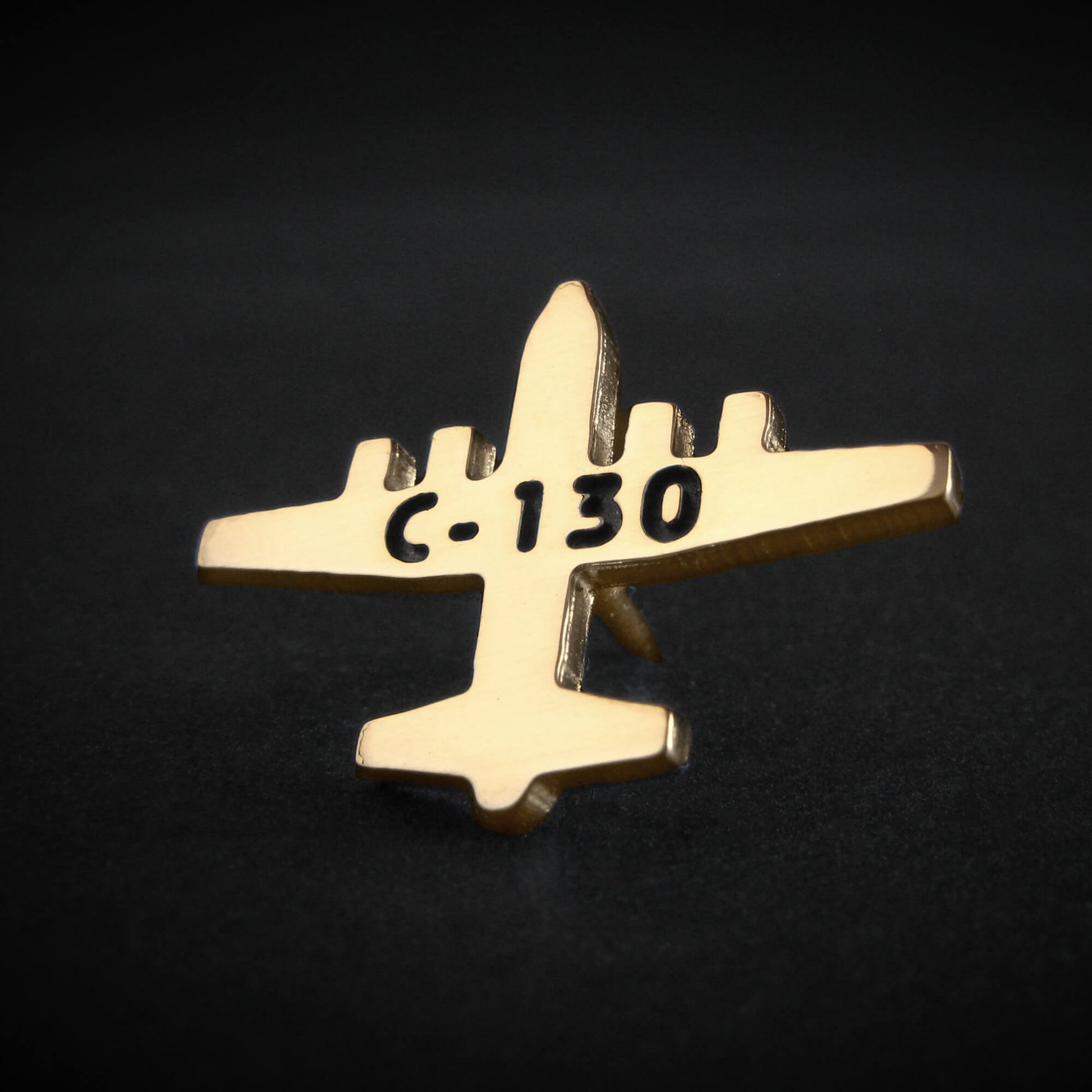 Gold C-130 airplane shaped lapel pin with 'C-130' text on a black background