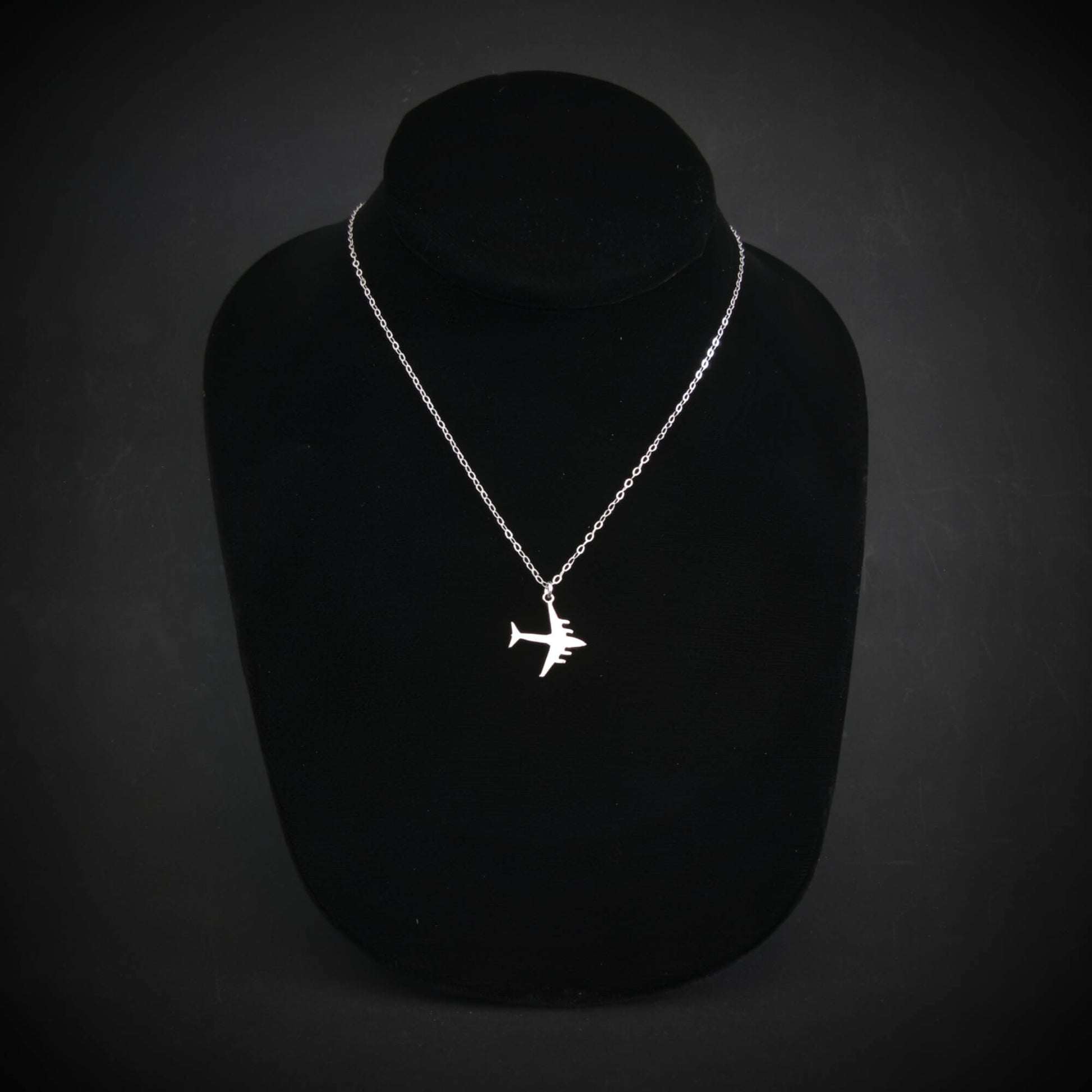 C-17 Globemaster military airplane pendant necklace in sterling silver, displayed on a black jewelry bust against a dark background.