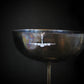 Silver C-130 necklace displayed on antique wine glass