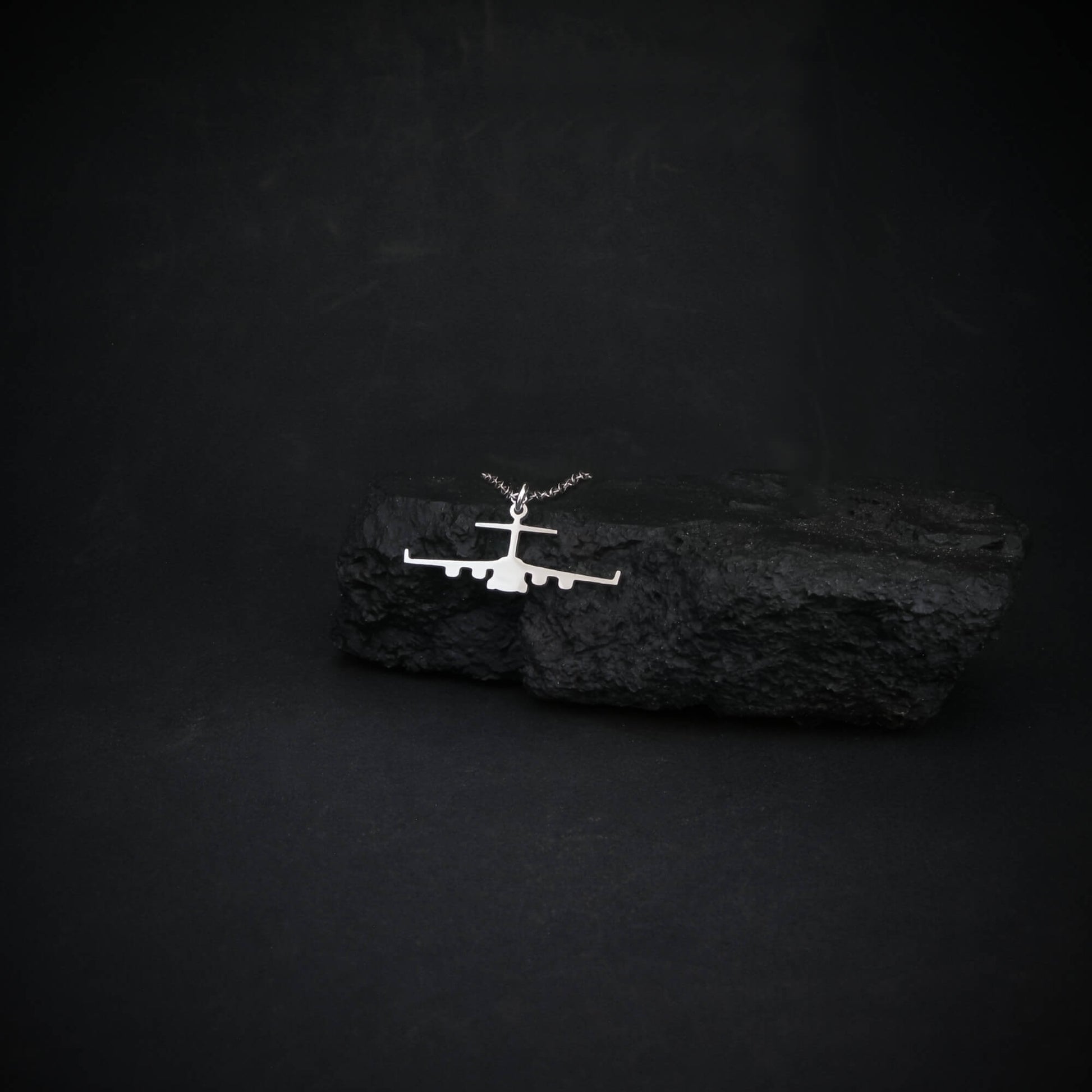 C-17 front silhouette necklace in sterling silver displayed on rugged black rock for contrast